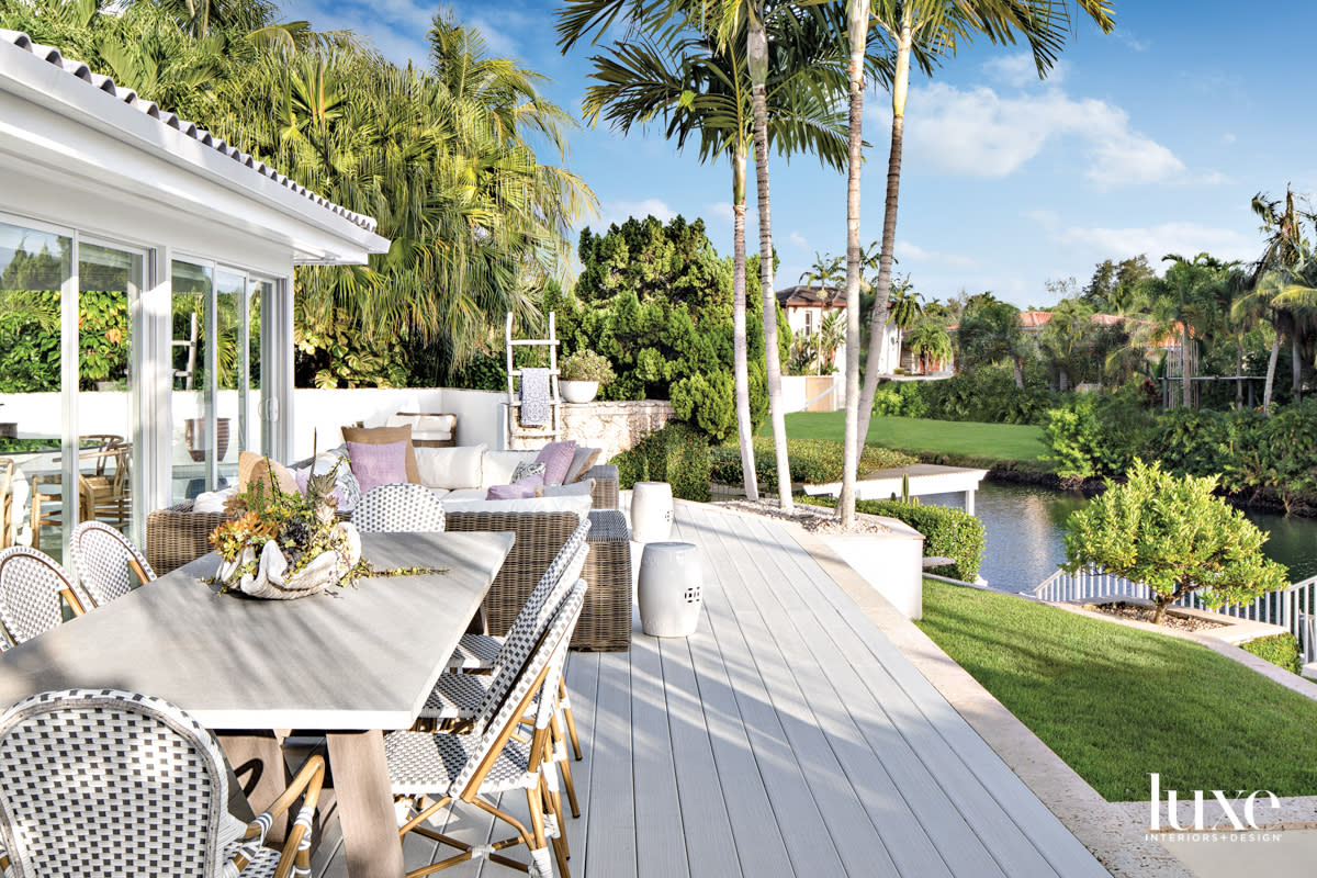 back patio overlooking waterway with dining table and wicker chairs