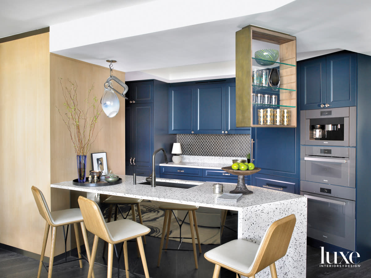 kitchen with blue cabinetry, wood wall, terrazzo countertop and barstools