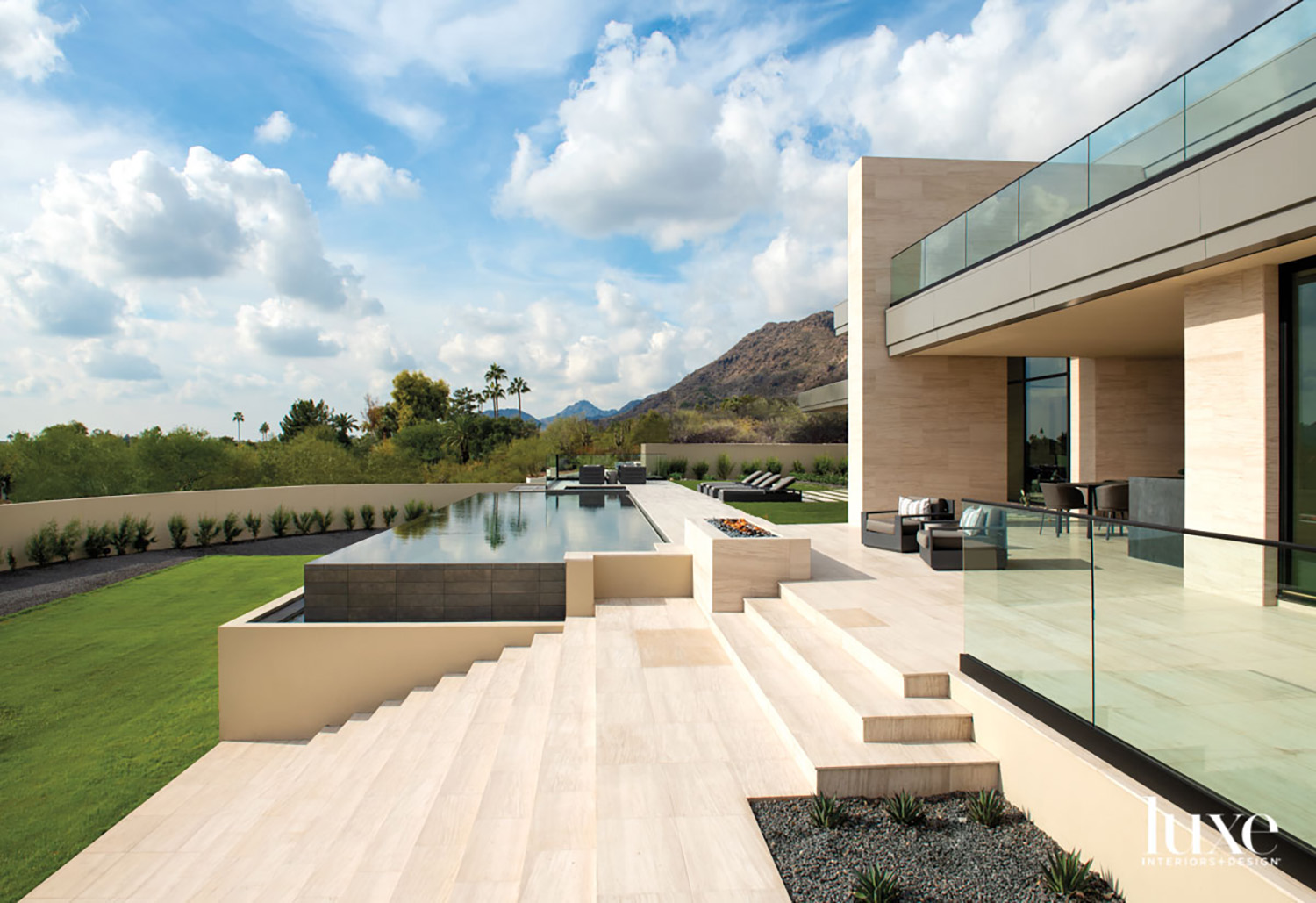 The exterior of a modern house with limestone steps to the yard and an infinity pool.