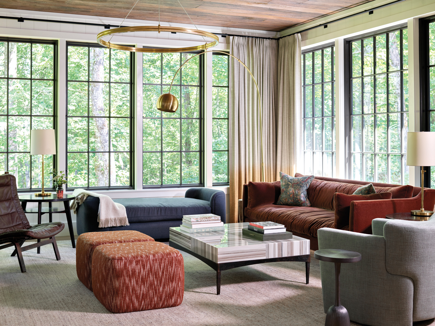 Living room with large windows, rust- and gray-colored upholstery, and a modern arc lamp