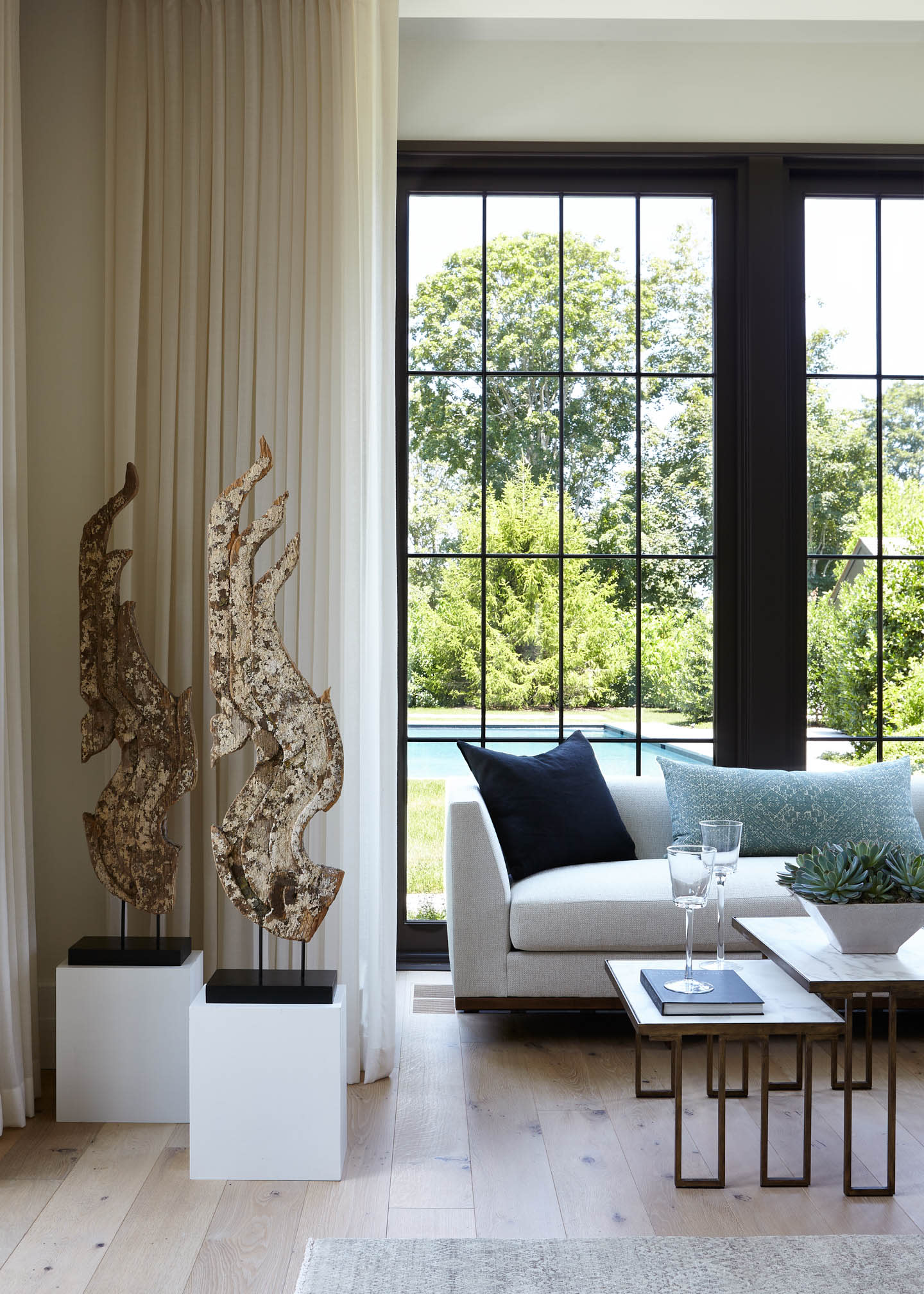 living room with two matching sculptural artworks next to a nesting coffee table and sofa