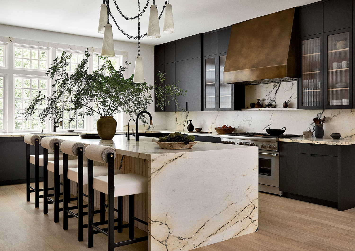 modern luxury kitchen with black cabinetry and a waterfall marble island
