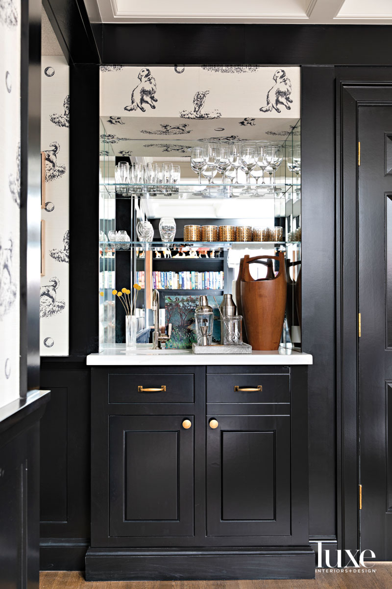 Bar area with black-painted cabinetry and glass backed shelving