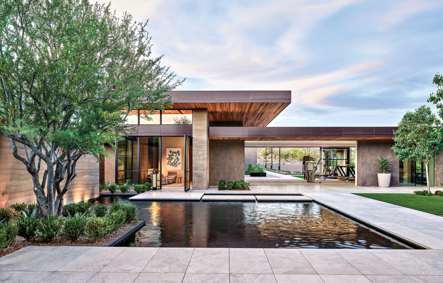 A courtyard in the center of a modern compound with a rectangular pool-like water feature