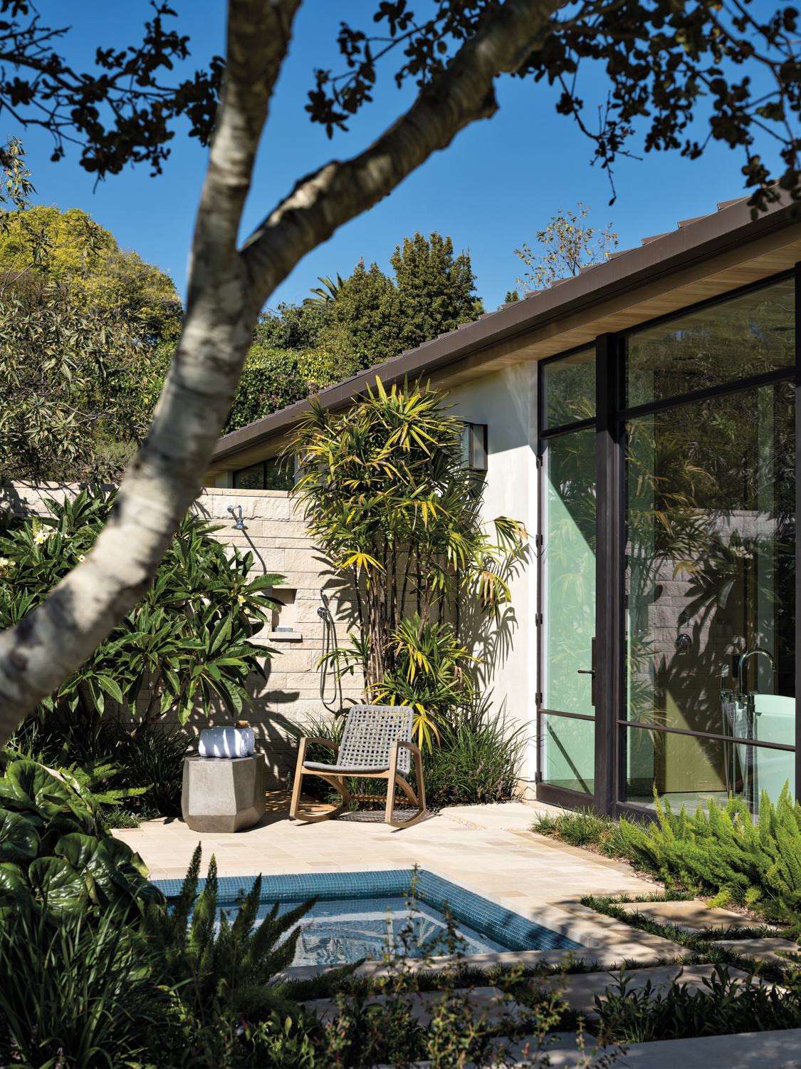 wellness room with a spa, and a grey rocking chair next to angular outdoor table