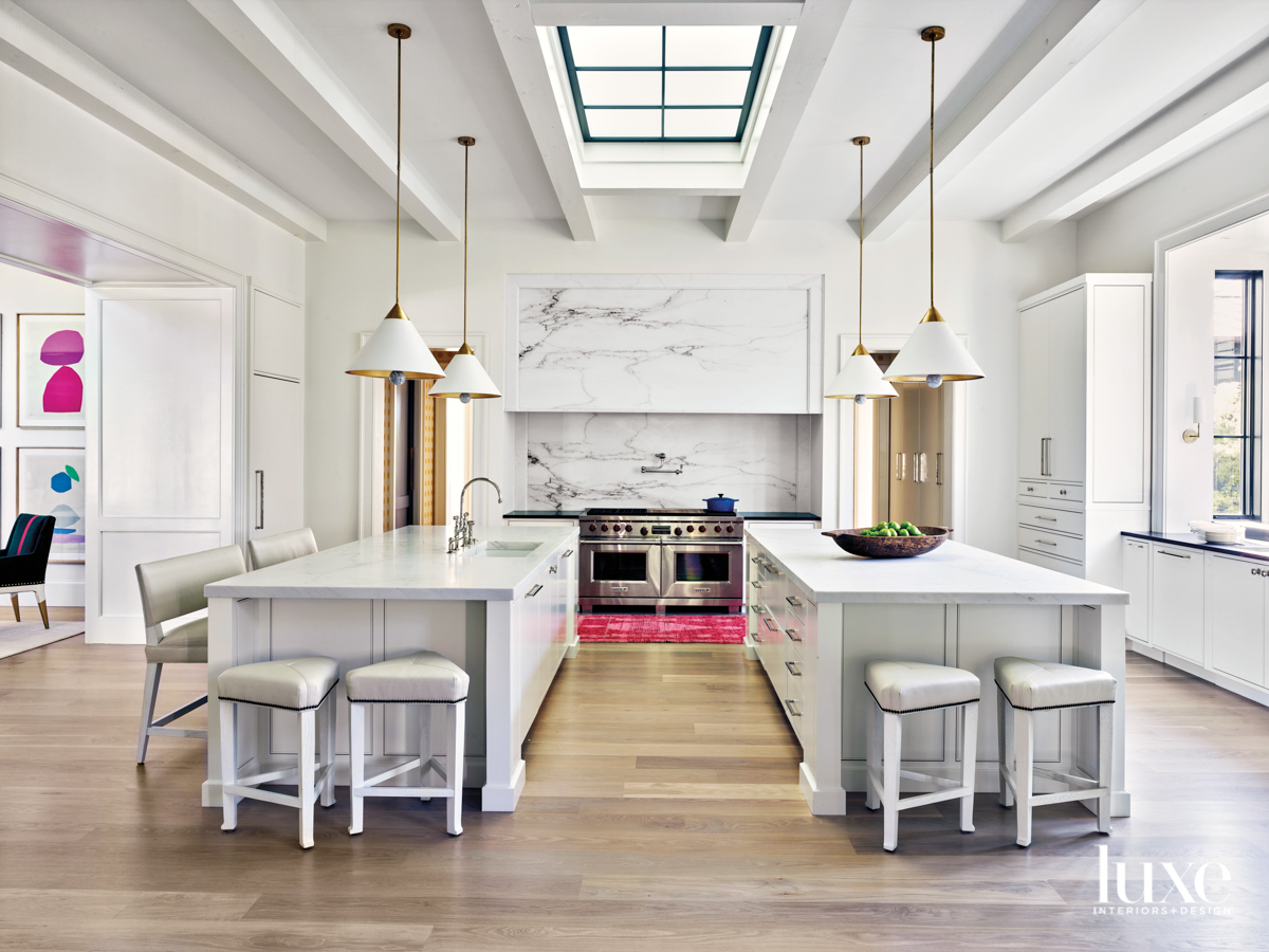 Open-format kitchen with skylight, a pair of islands, double ovens and four contemporary ceiling pendants