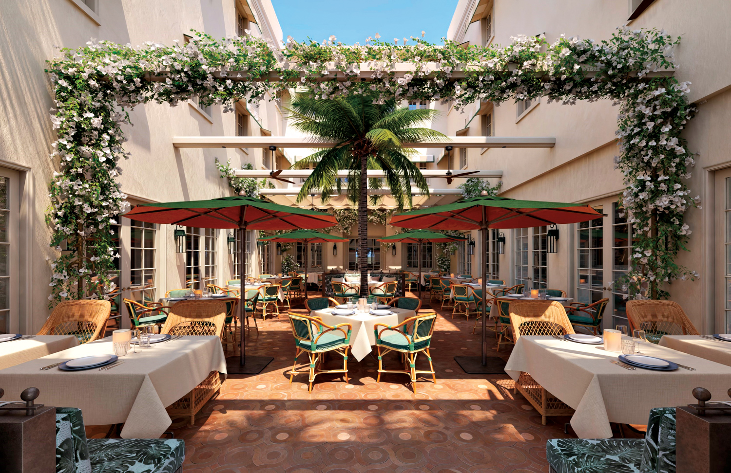 Outdoor dining area with wicker chairs between U-shaped building with a floral arch over the patio