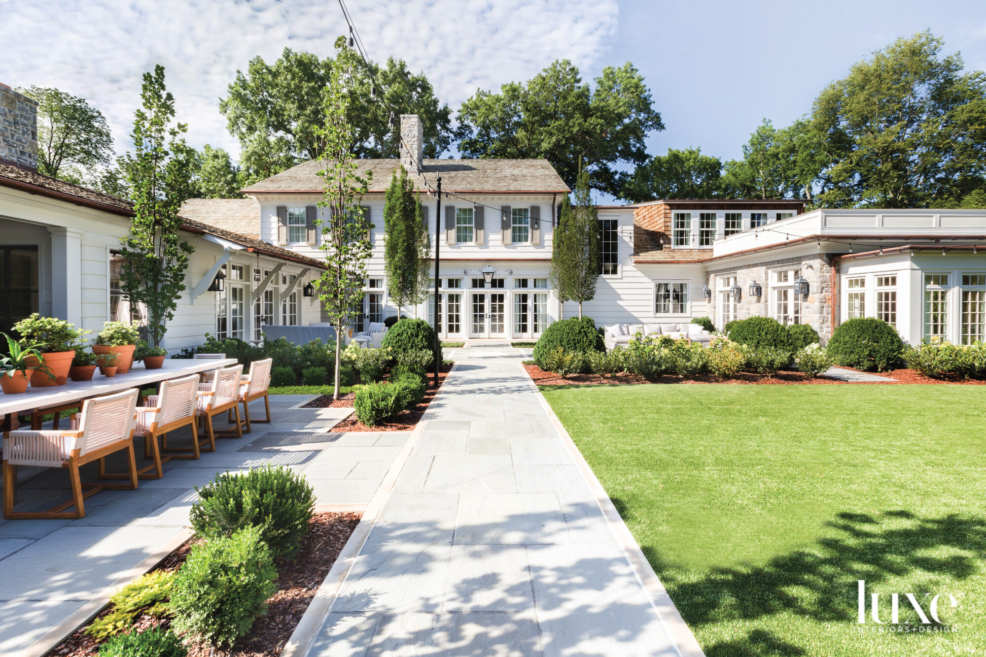 Exterior of house with green grass, sidewalk and outdoor dining table