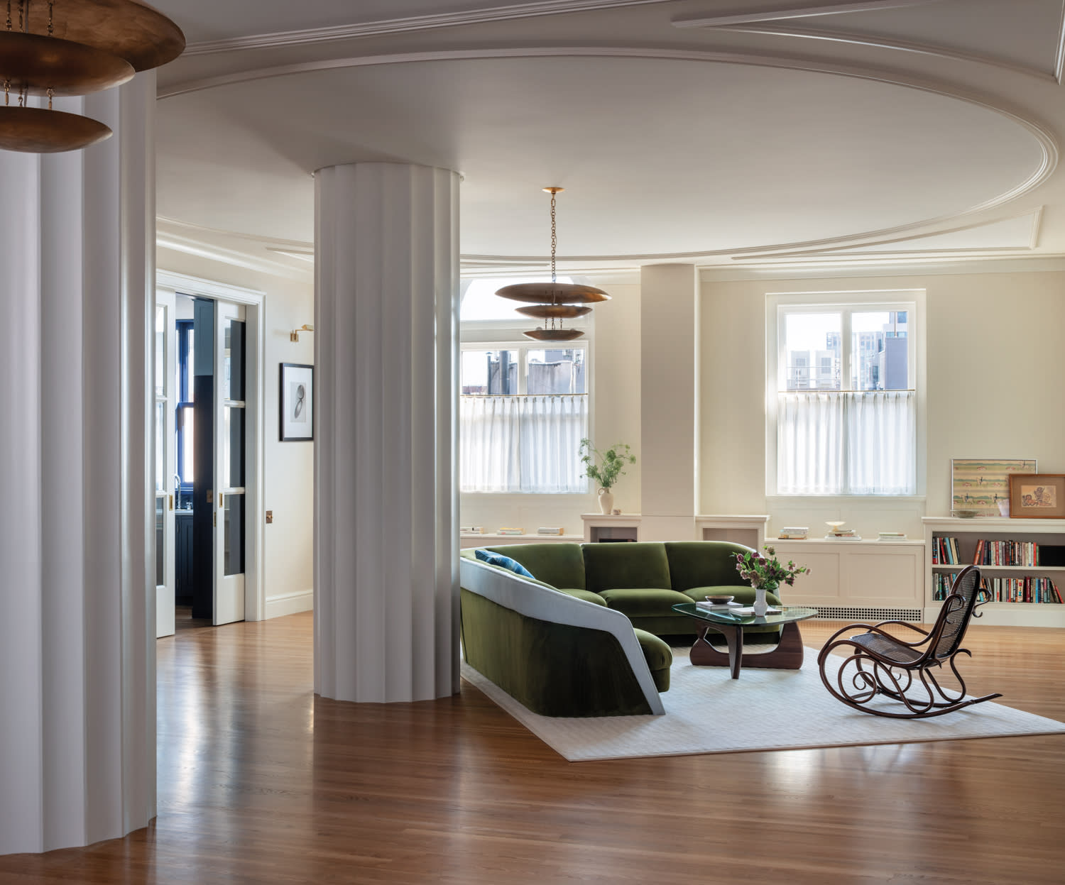 grand living room in a New York City apartment with columns and a green post-modern sectional