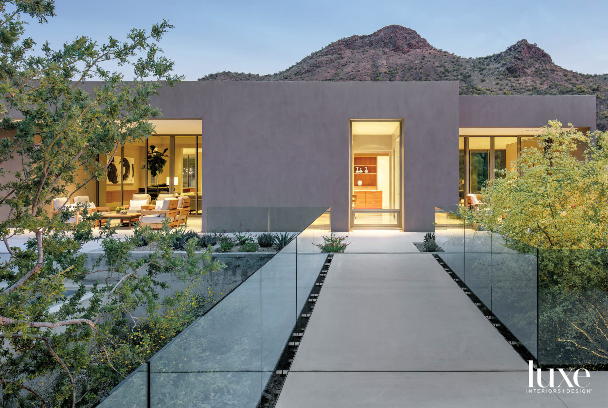 A view of a modern house from the outside with a mountain behind it.