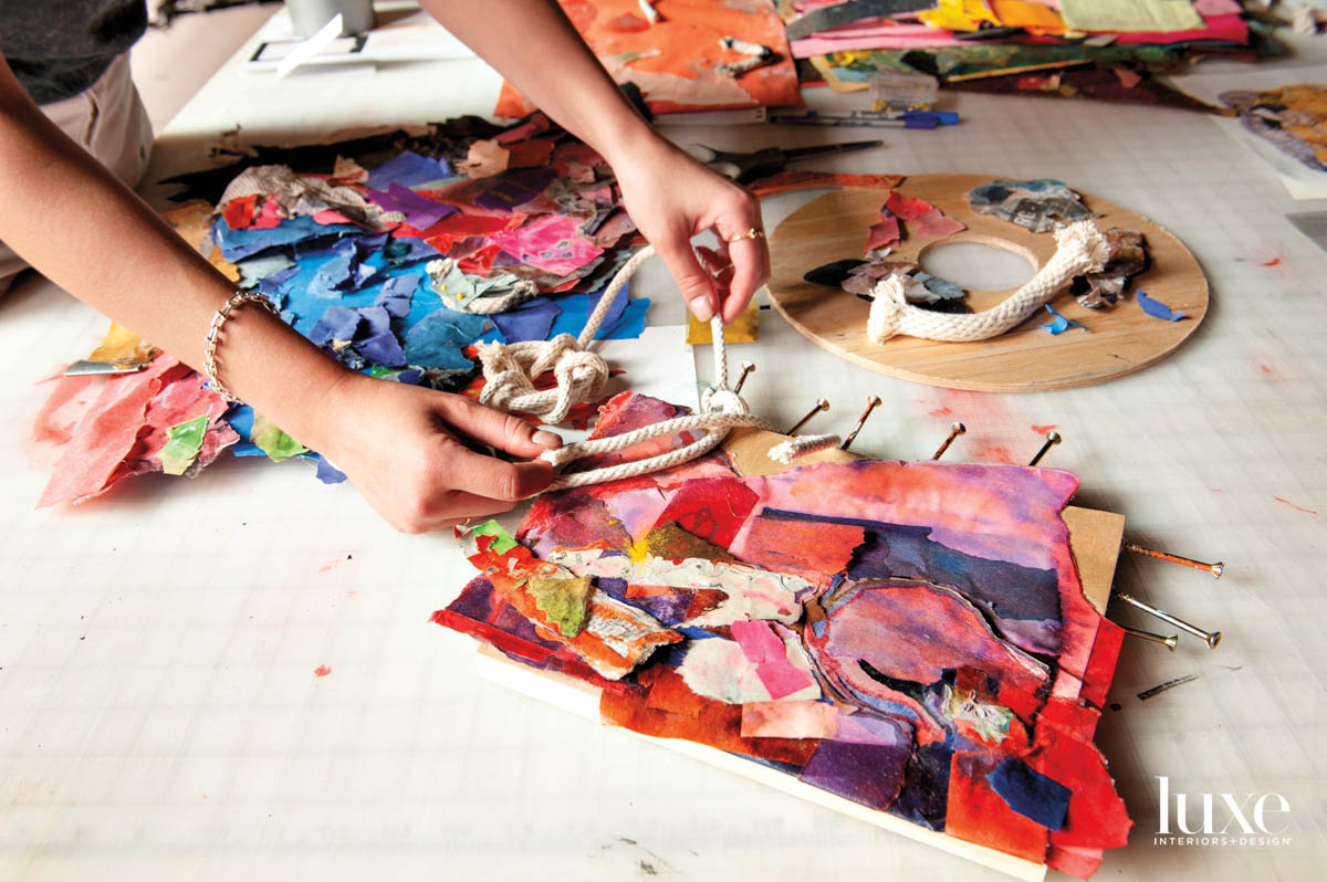 A woman's hands weaving rope around a piece of art.