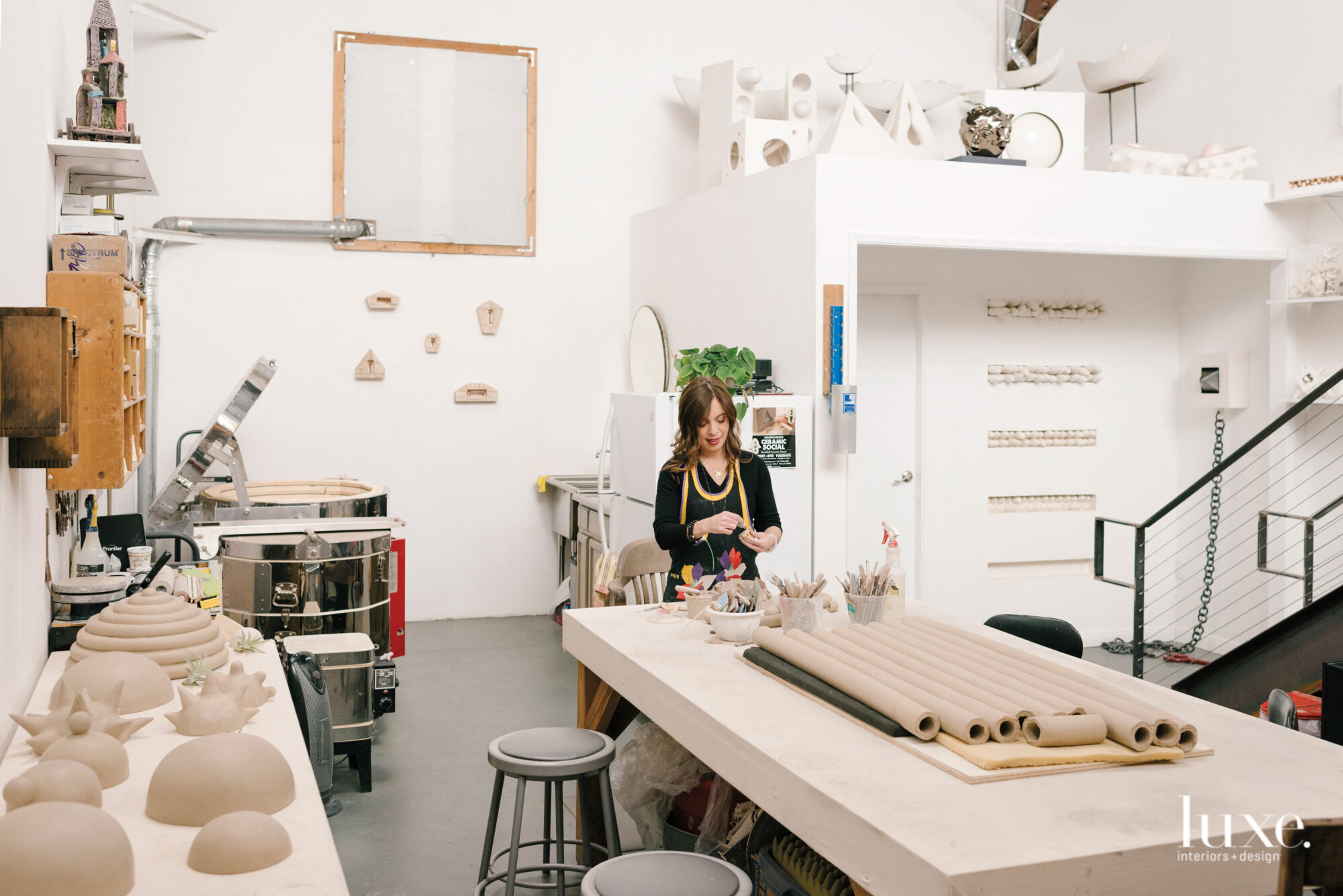 Elizabeth Orleans stands at her work table with unfinished ceramic pieces