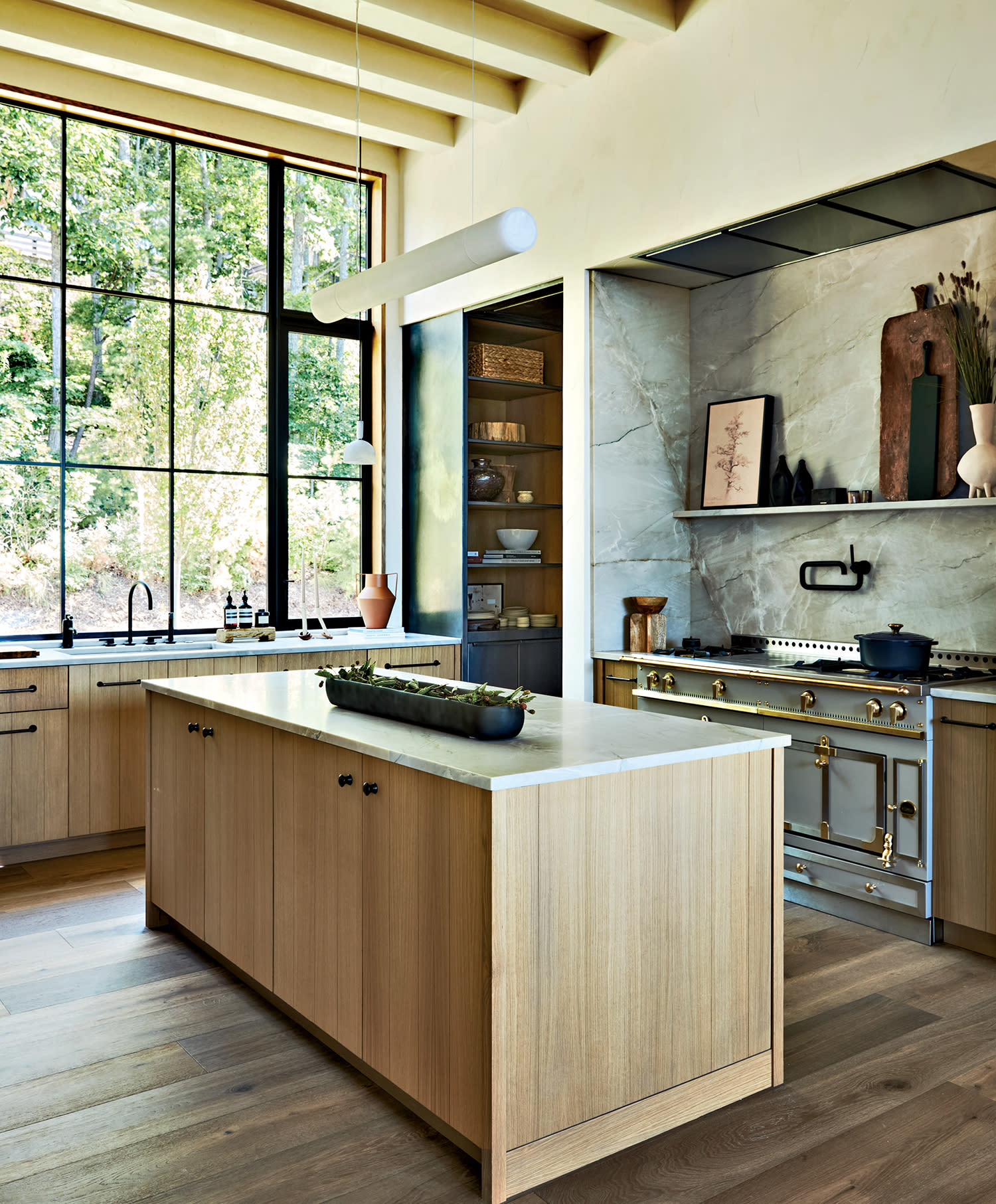 An island with wood cabinets and a quartzite countertop sits at the center of a kitchen