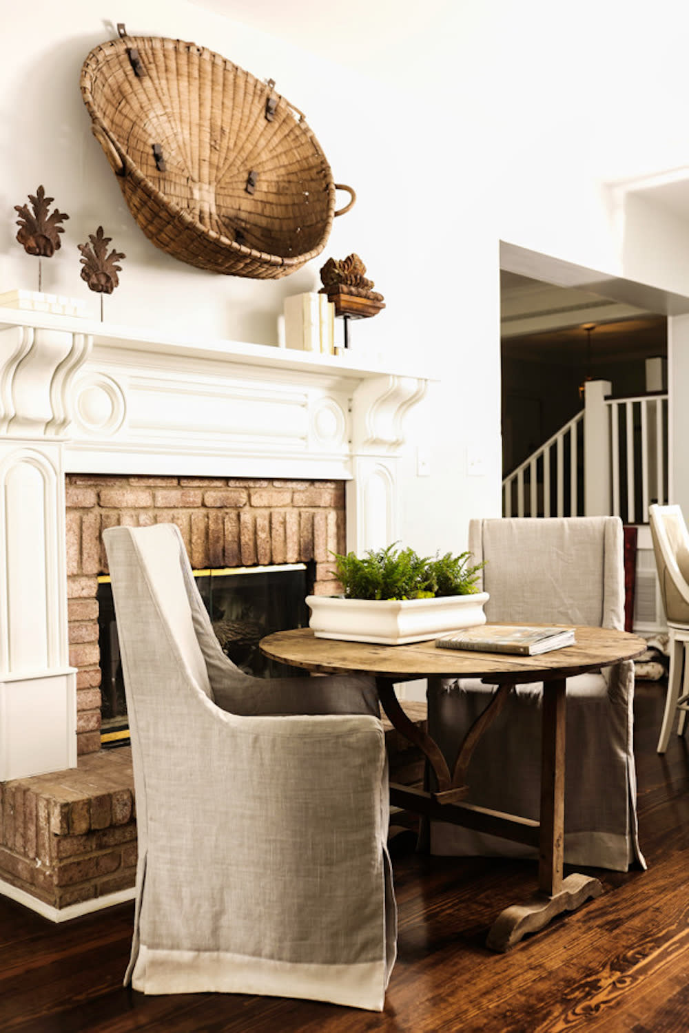 Linen slipcovered chairs nestled into an antique wine table in this kitchen makes for the perfect sitting area to enjoy coffee fireside.