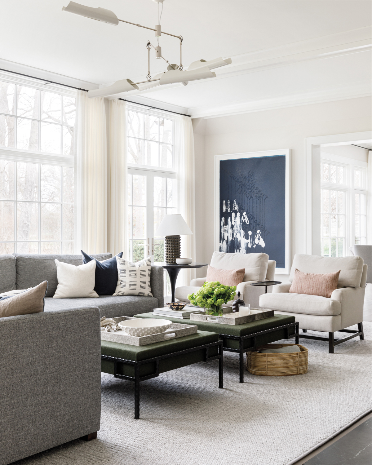 living room with gray sectional, two cream armchairs and blue-and-white abstract painting