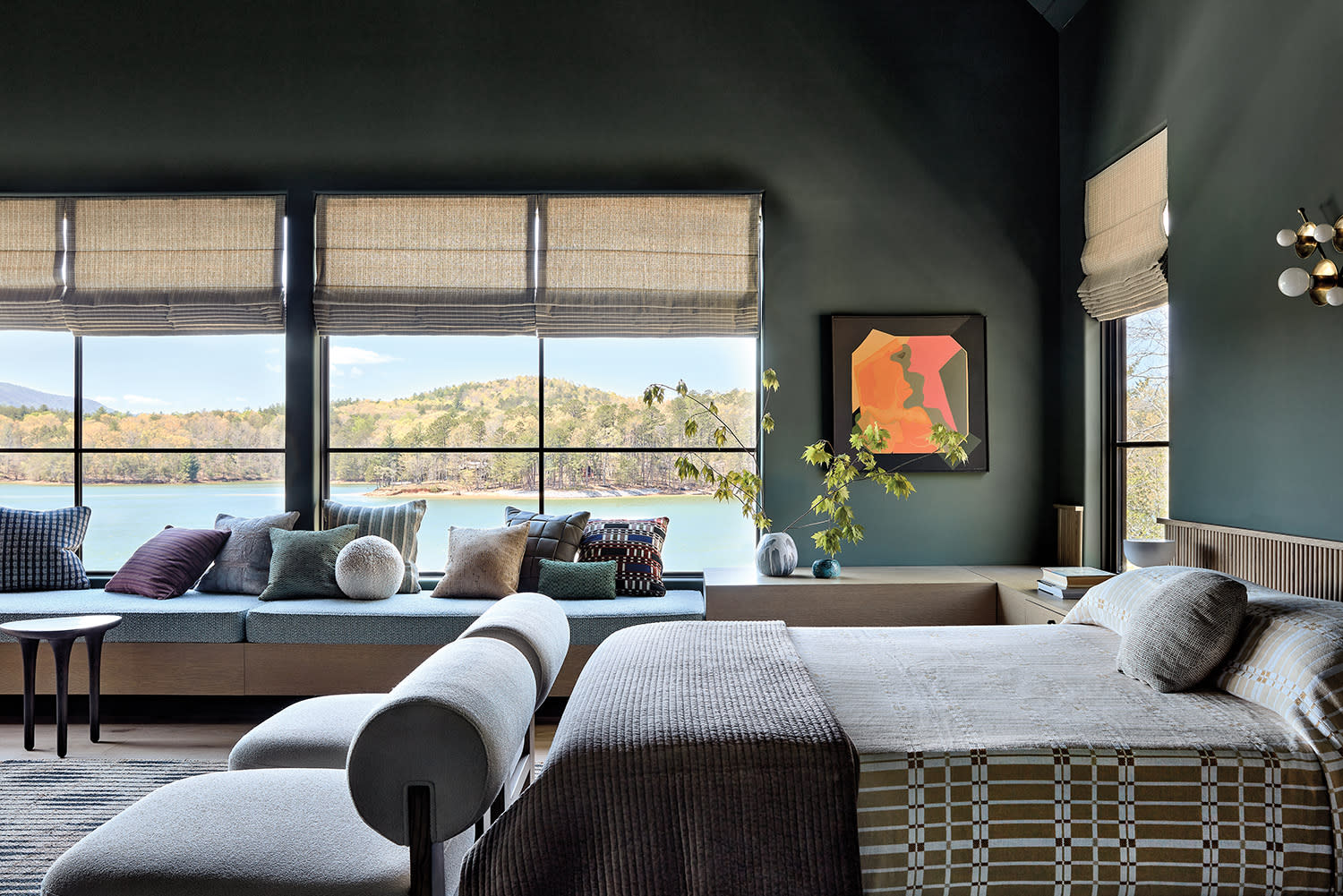 moody green guest bedroom with views of a lake out the window