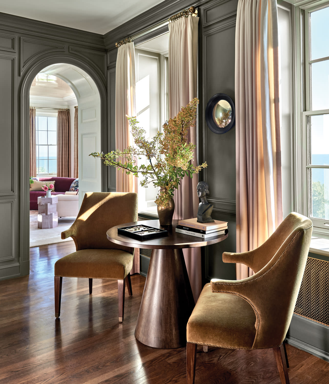 moody home library corner with mustard-colored armchairs around a coffee table