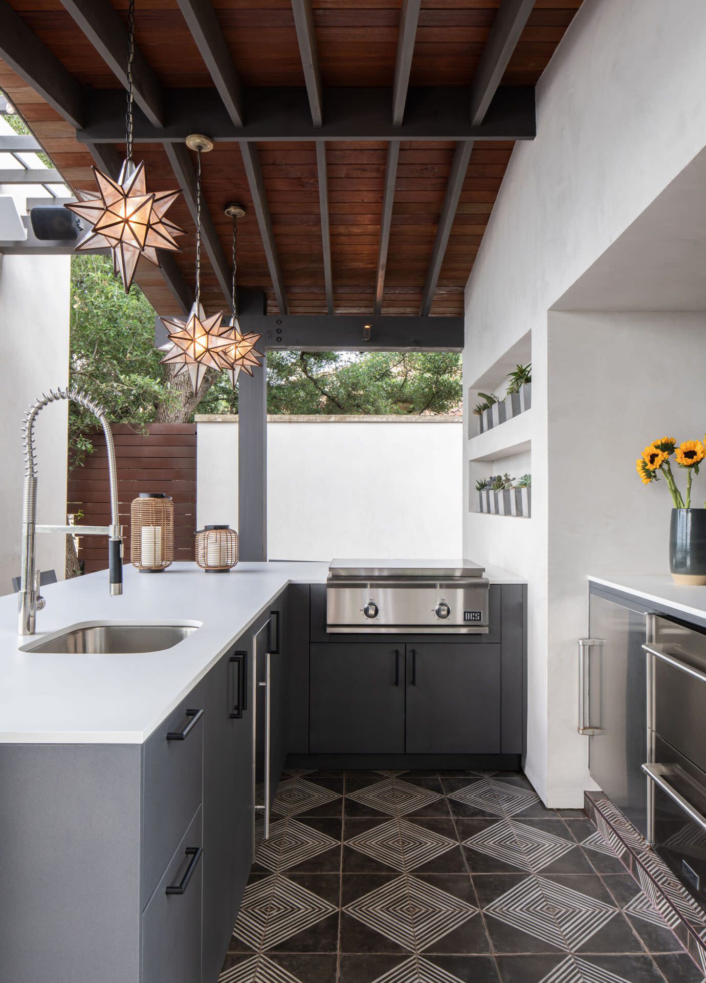an outdoor kitchen with pendant star lighting and a grill in countertop