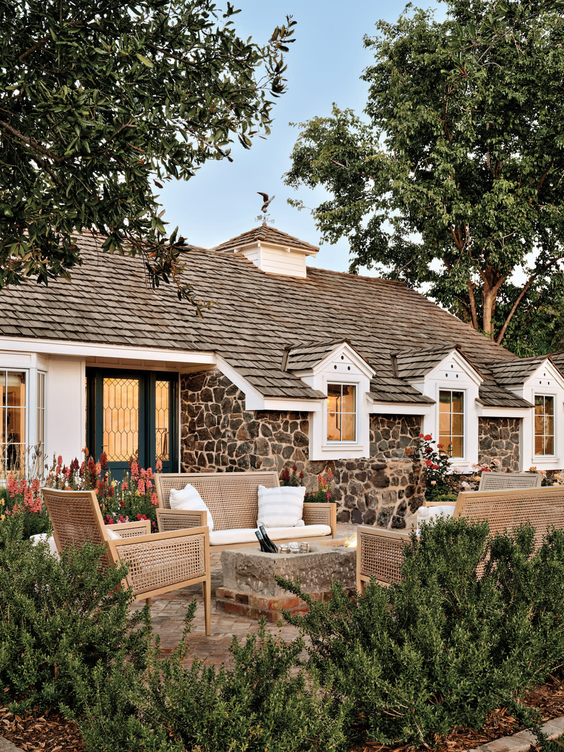 Outdoor seating surrounds a limestone trough holding beverages on the patio of a stone cottage