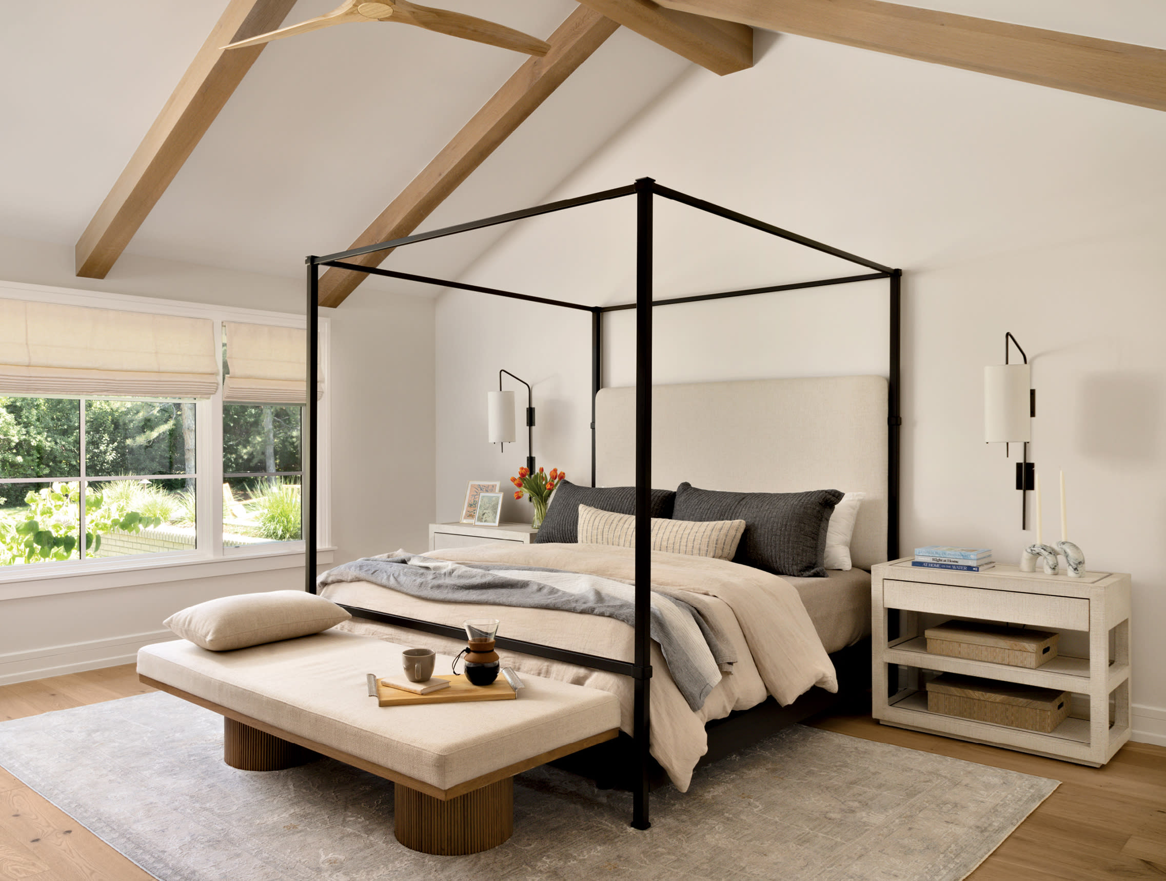 neutral bedroom with a metal canopy bed and exposed beams on the ceiling