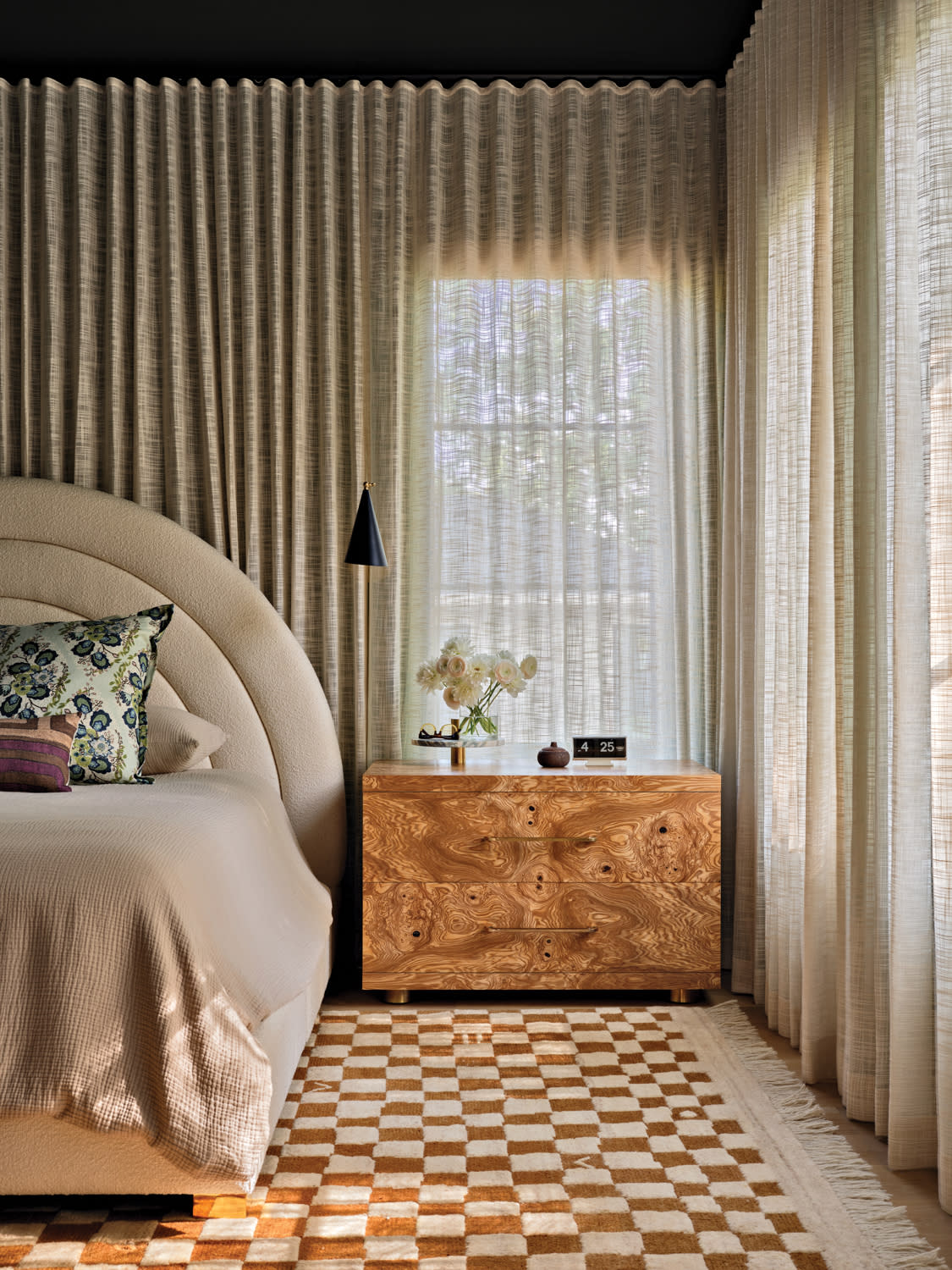 modern bedroom with a curved headboard and a checkerboard patterned rug