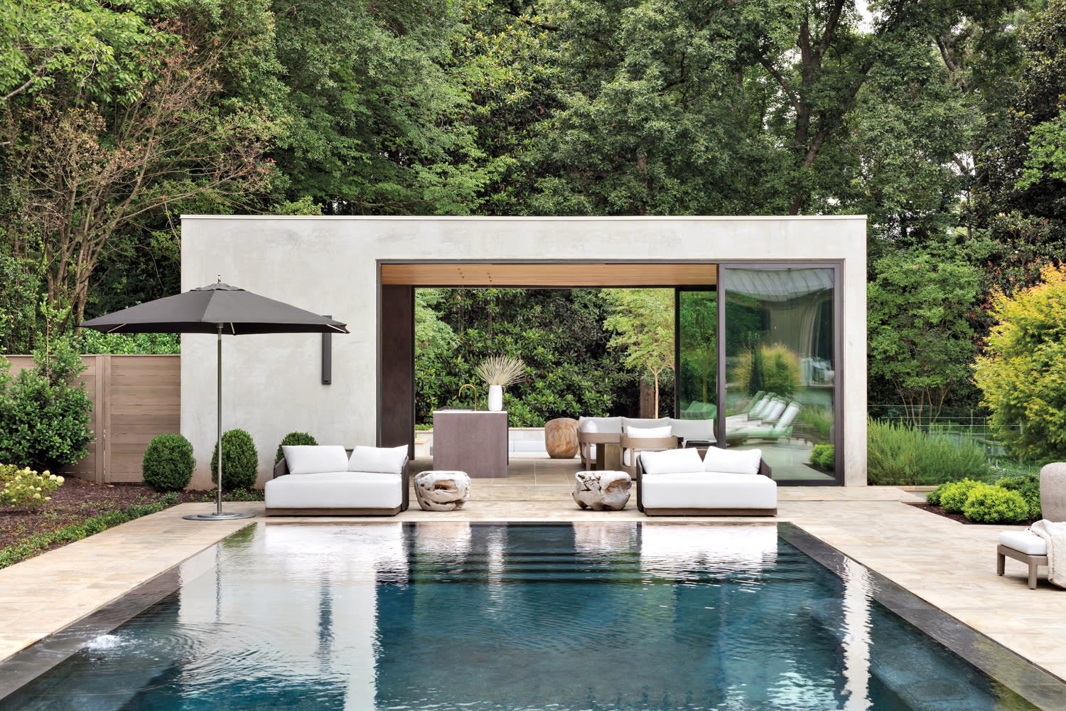 Modern pool house with open glass doors and sun loungers