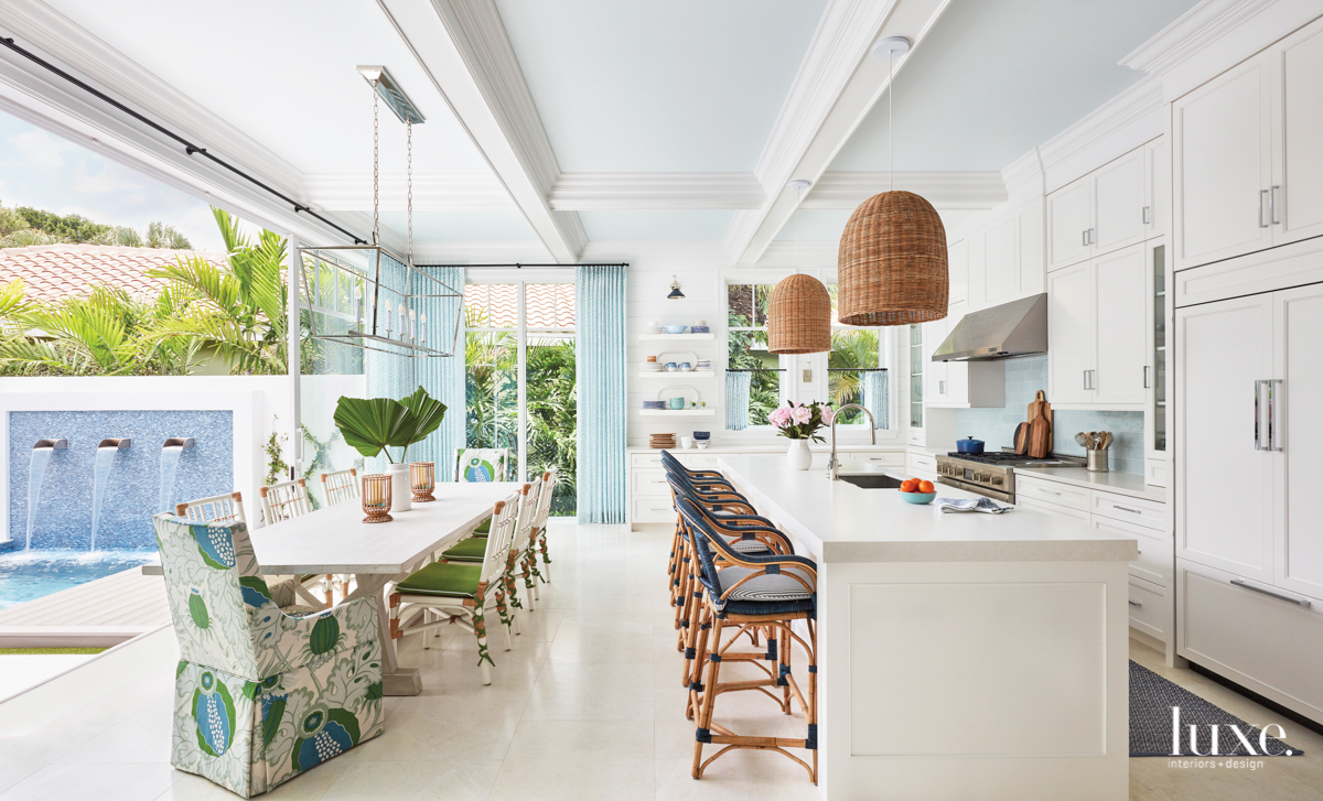 White kitchen and dining area with blue patterns and wicker accents.