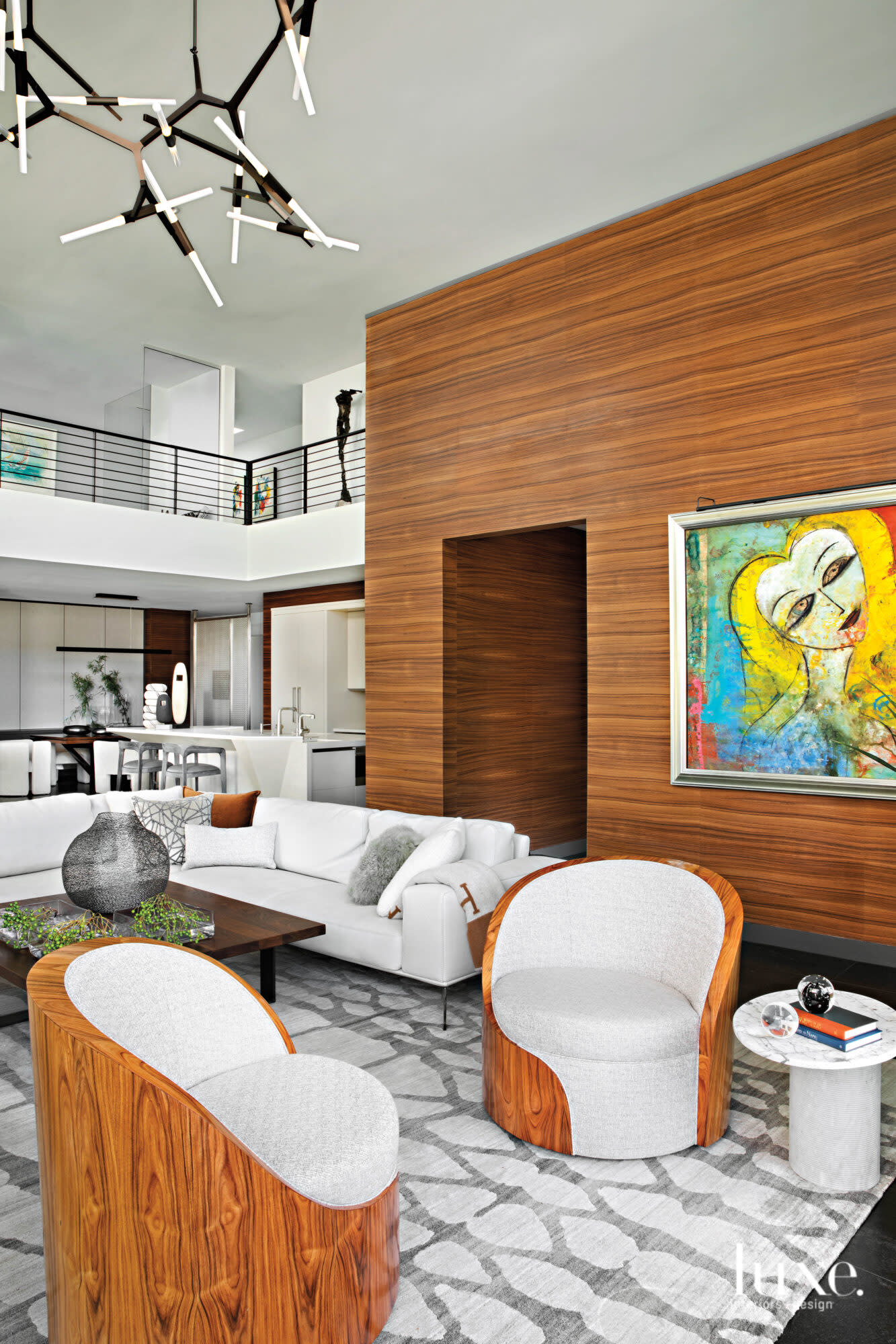 The double-height living room with a modern painting by Jamali hanging on a wood veneer wall.