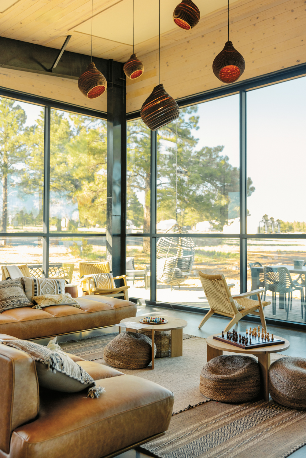 Living space with leather sofas, layered rugs and poufs enclosed by window walls