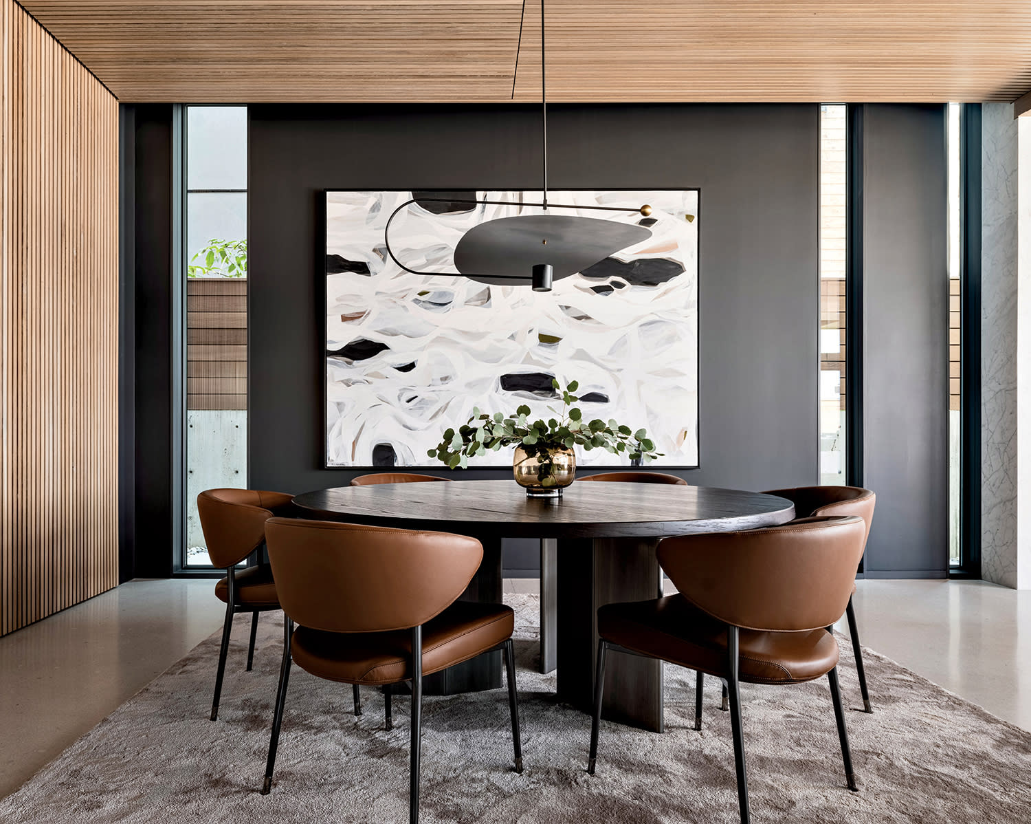 modern dining room wrapped with oak slats, leather chairs and a black table