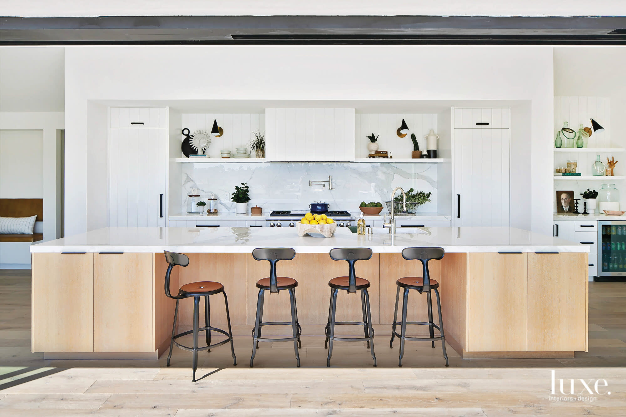 Shot of kitchen island and barstools facing the stove and hood