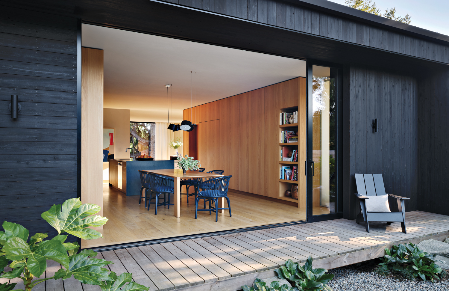 home clad in Nakamoto Forestry shou sugi ban wood siding with a sliding door opening to the deck