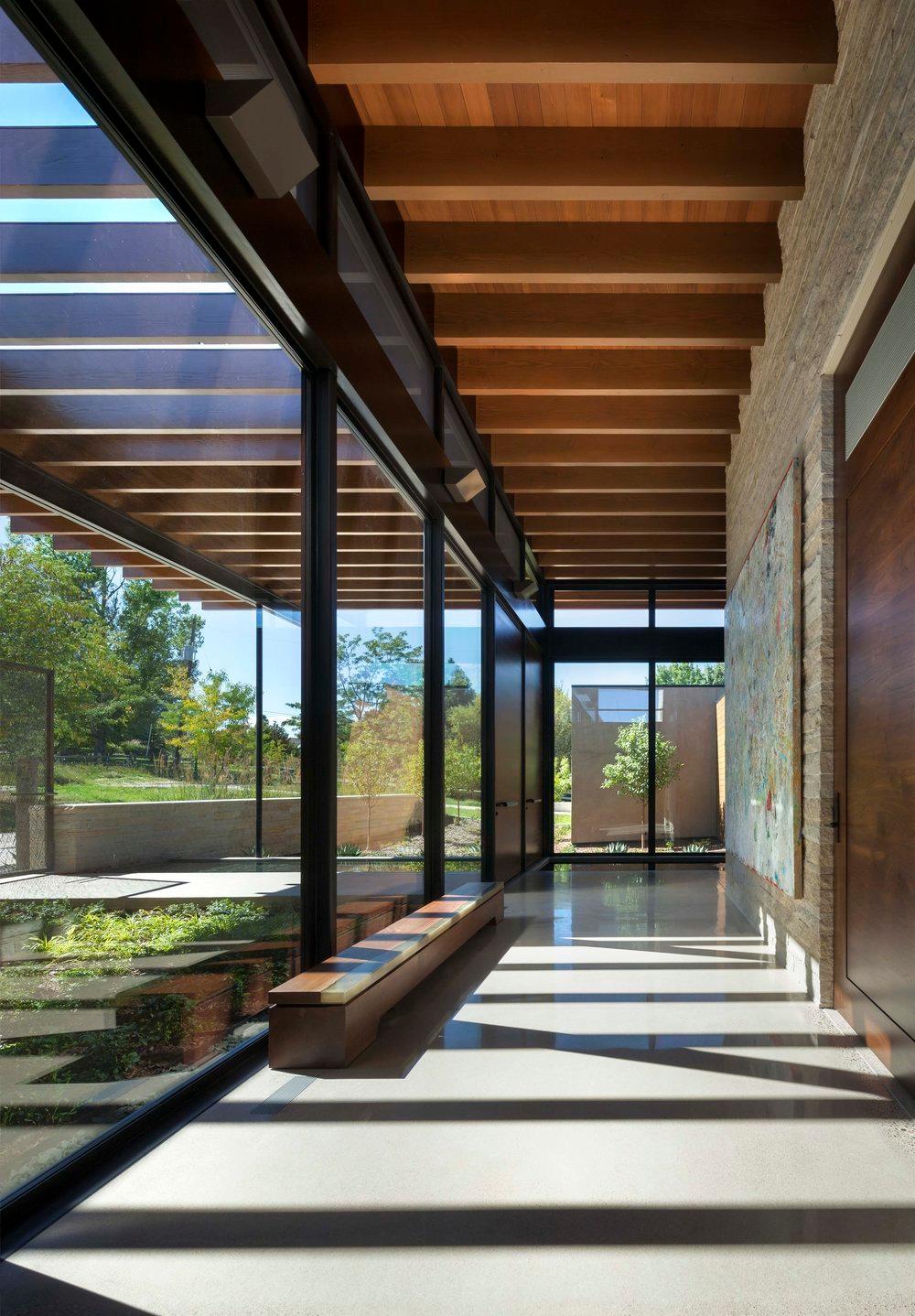 Large hallway with floor to ceiling windows, polished concrete floors, wood and steel beams that extend from inside out.