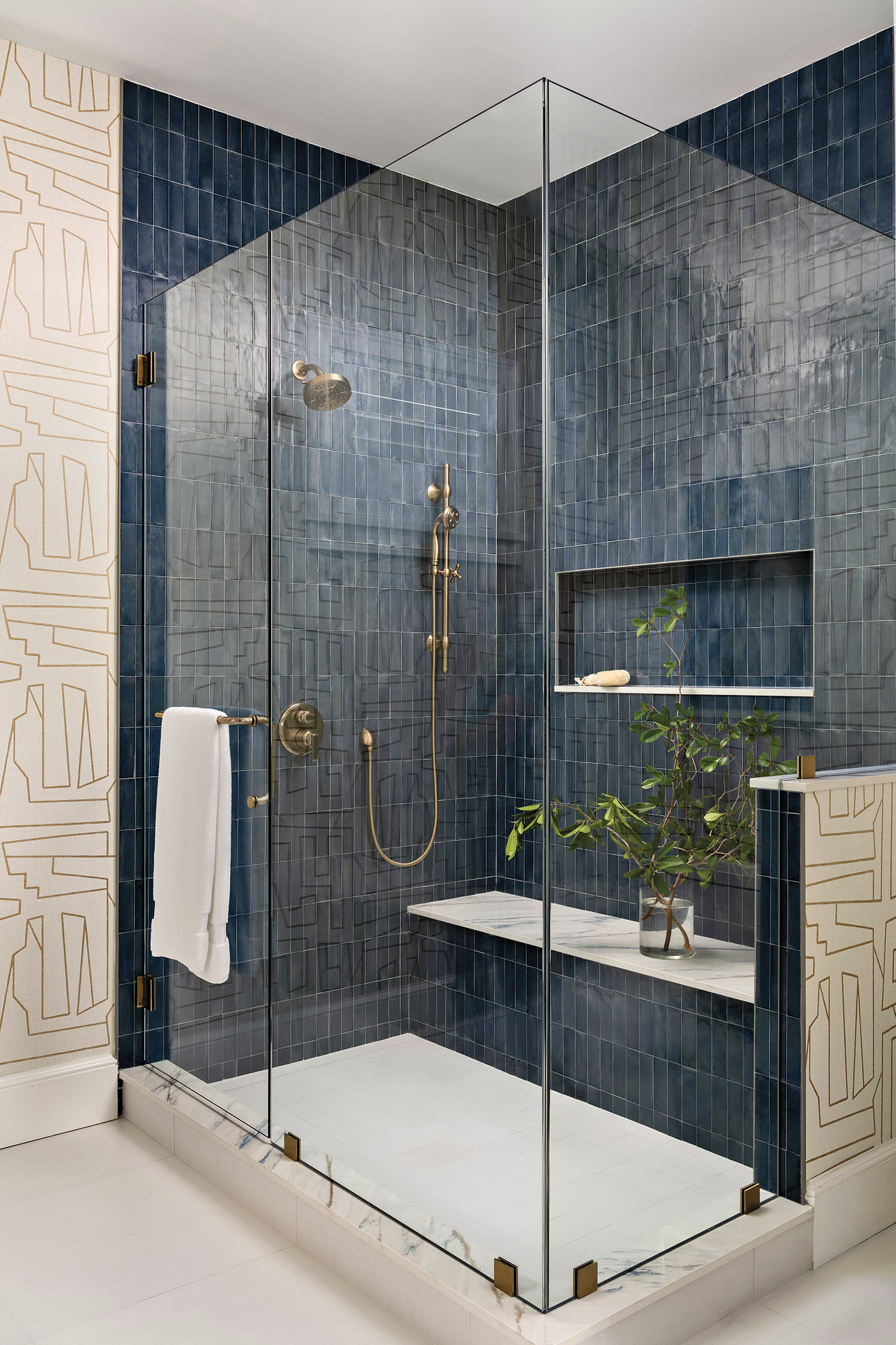 Elegant bathroom with a glass-enclosed shower, blue tiles, and gold fixtures