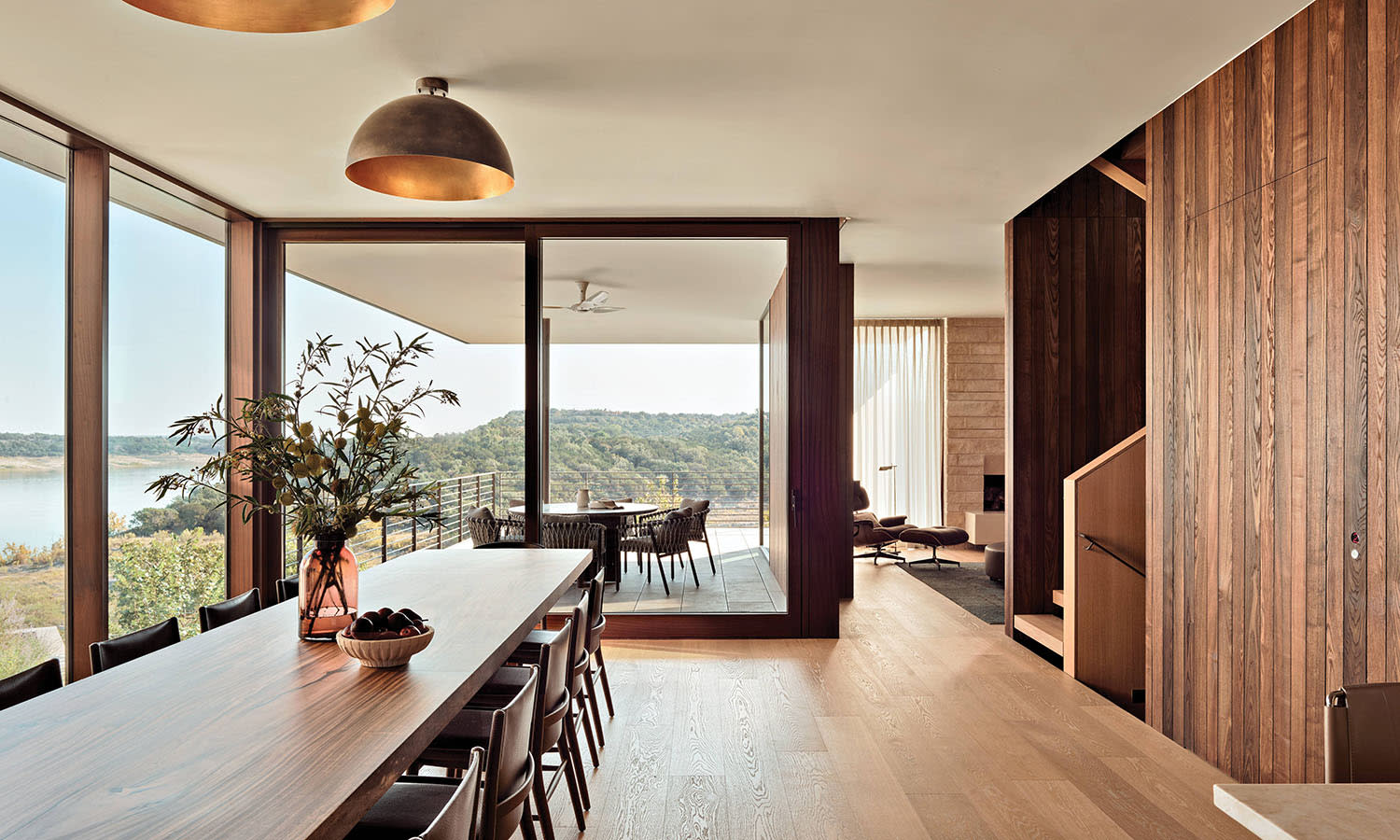 oak floored dining room with a long family table and glass walls