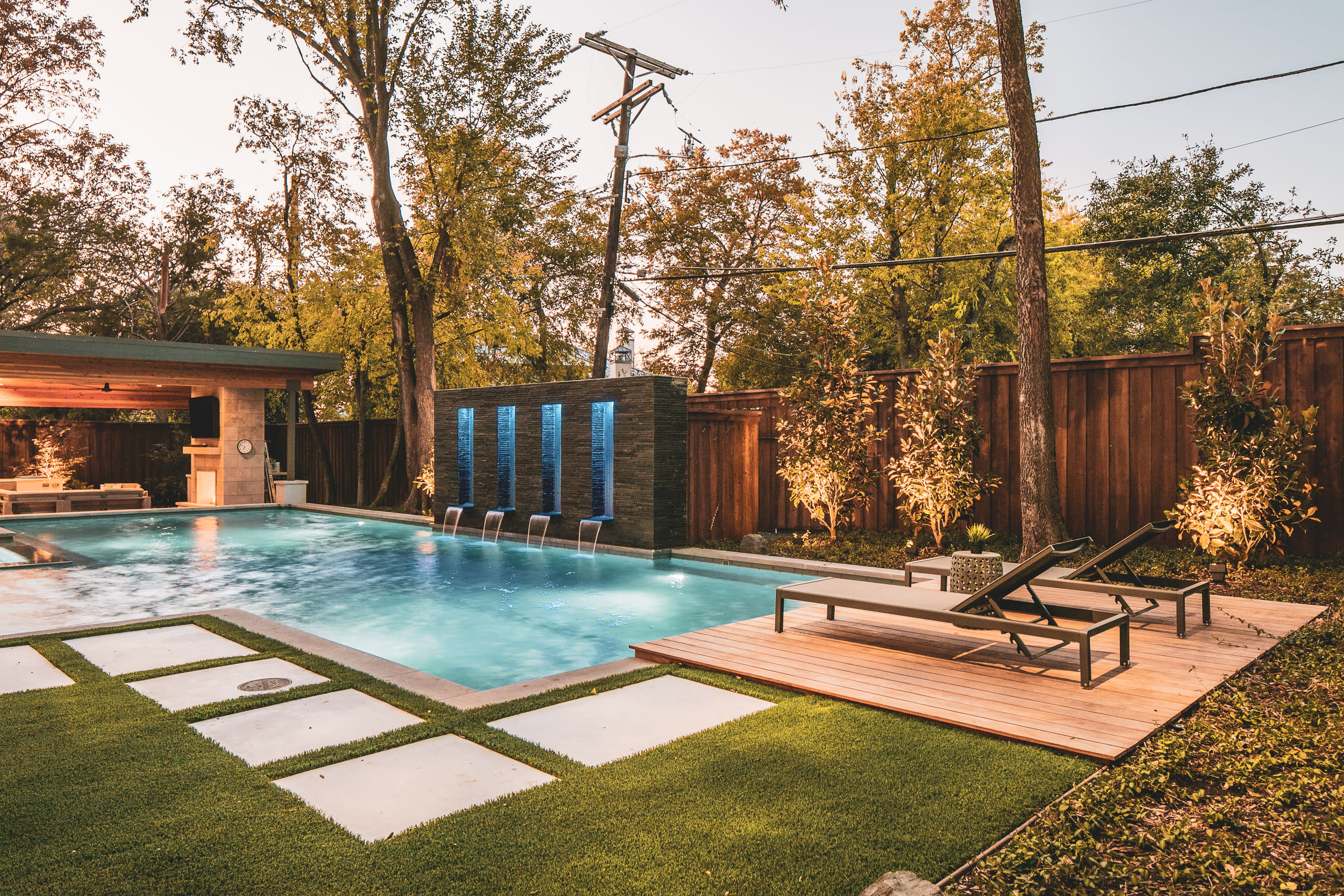 Backyard pool with trio of waterfalls and privacy trees