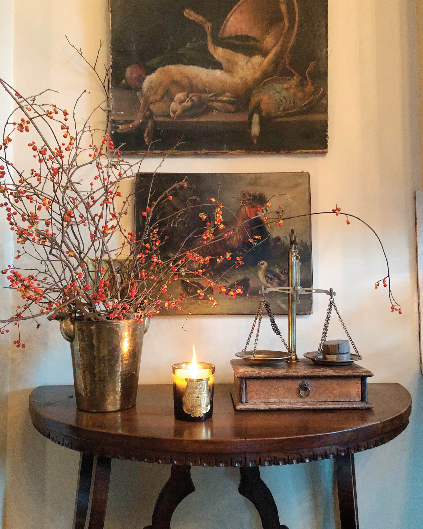 small table with artwork above and tall flowers