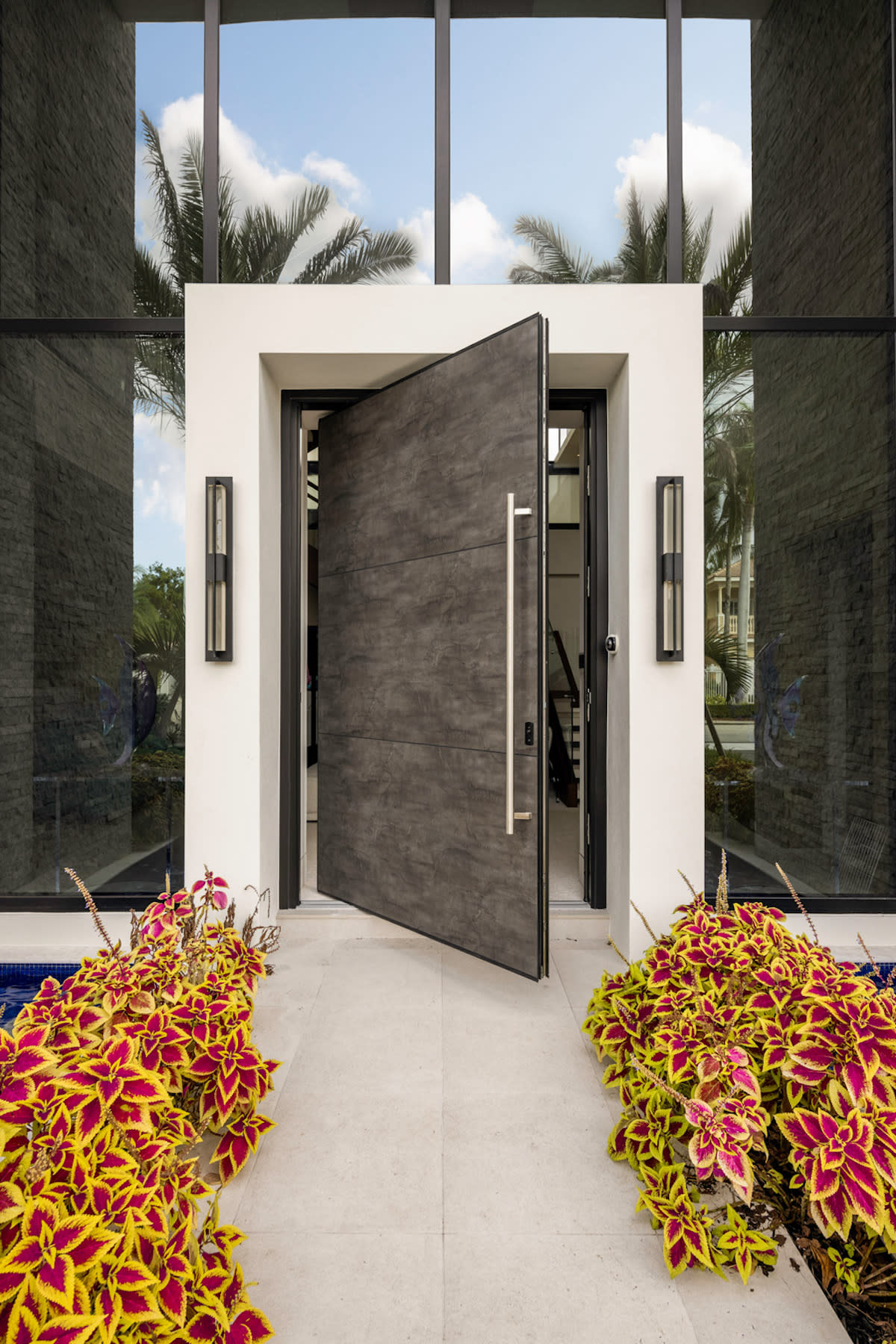 A contemporary front door adorned with vibrant flowers and lush plants, creating a welcoming entrance.