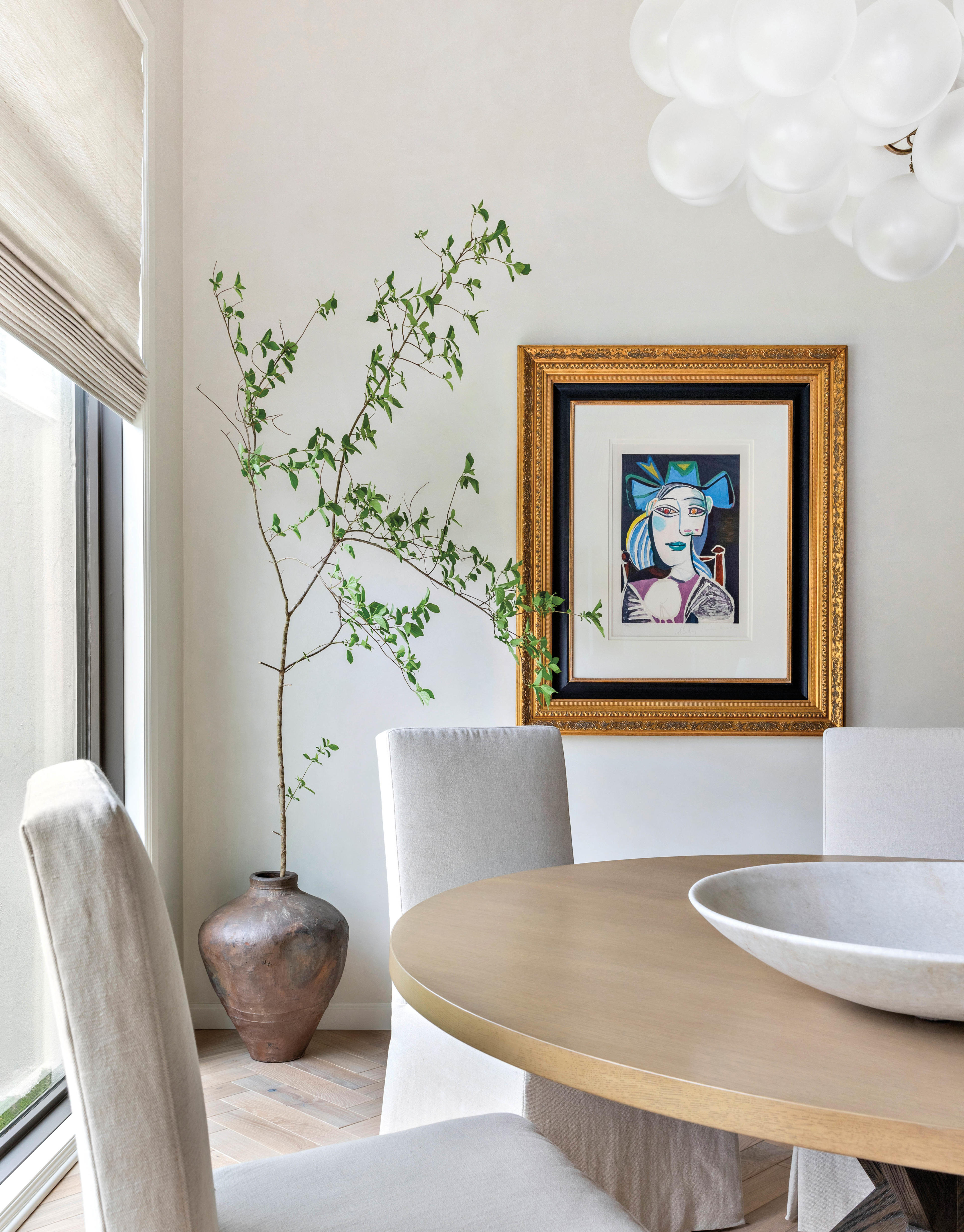 wood game table with white linen-covered chairs and picasso lithograph in background