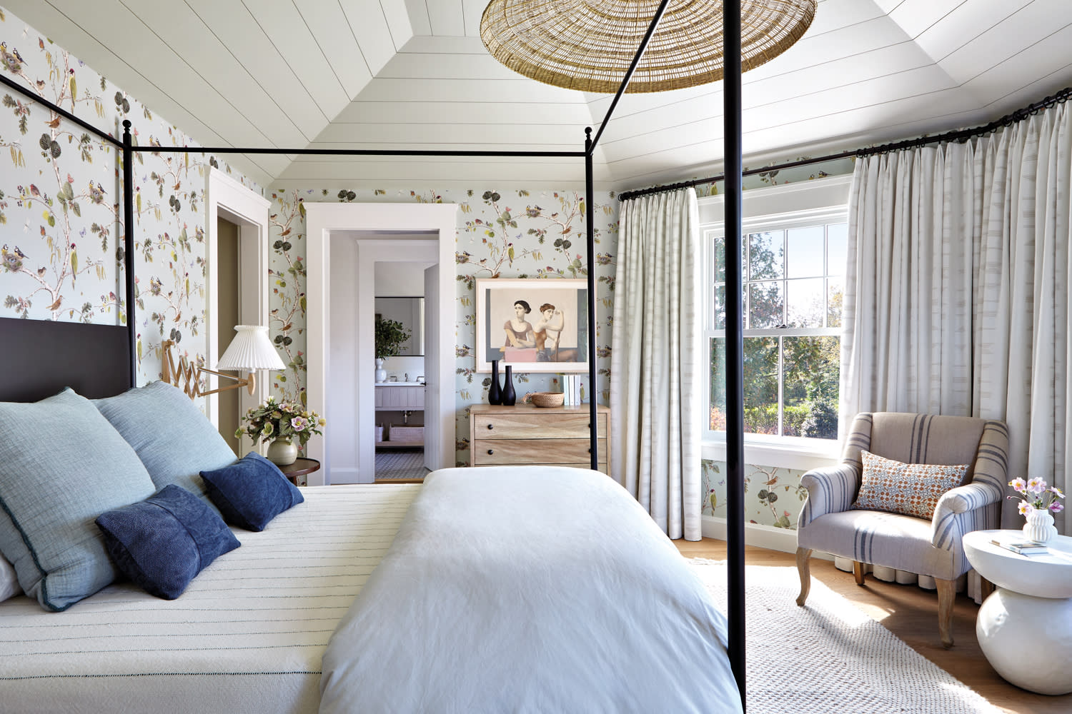 a woven pendant hang above a canopy bed in a floral wallpapered bedroom