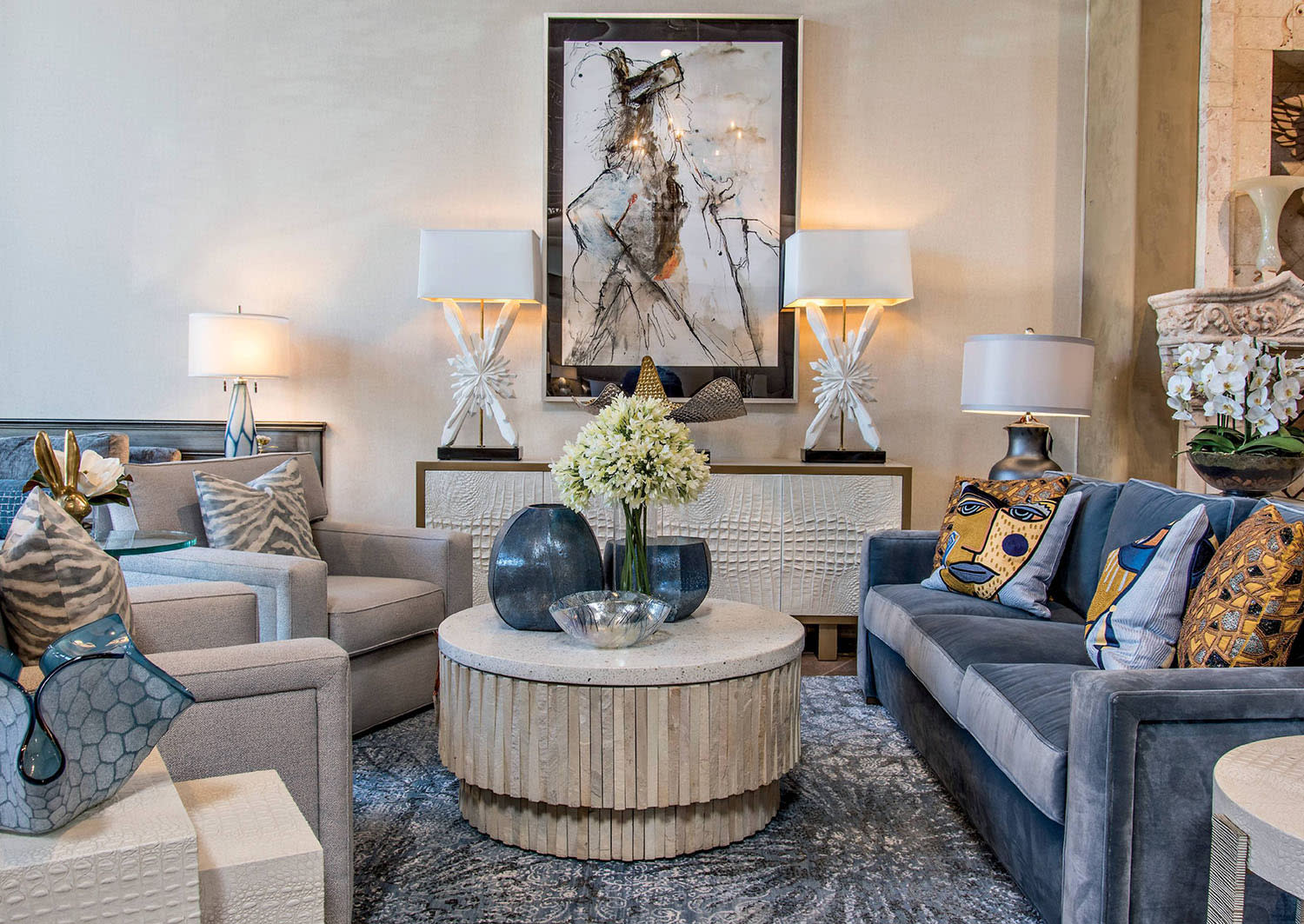 A couch and armchairs surround a round coffee table styled flowers and decorative bowls.