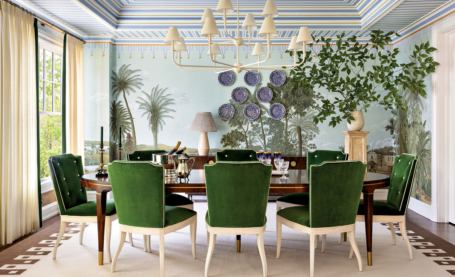 dining room with a jungle-themed wallcovering and green dining chairs