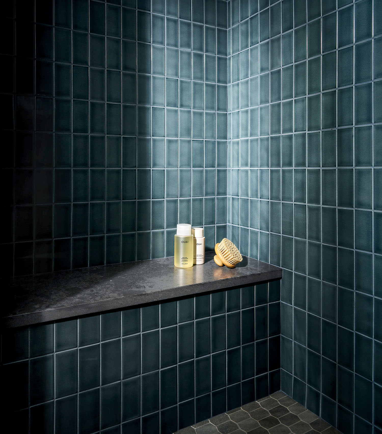 A bathroom featuring blue tiles and a sleek black bench against the wall.