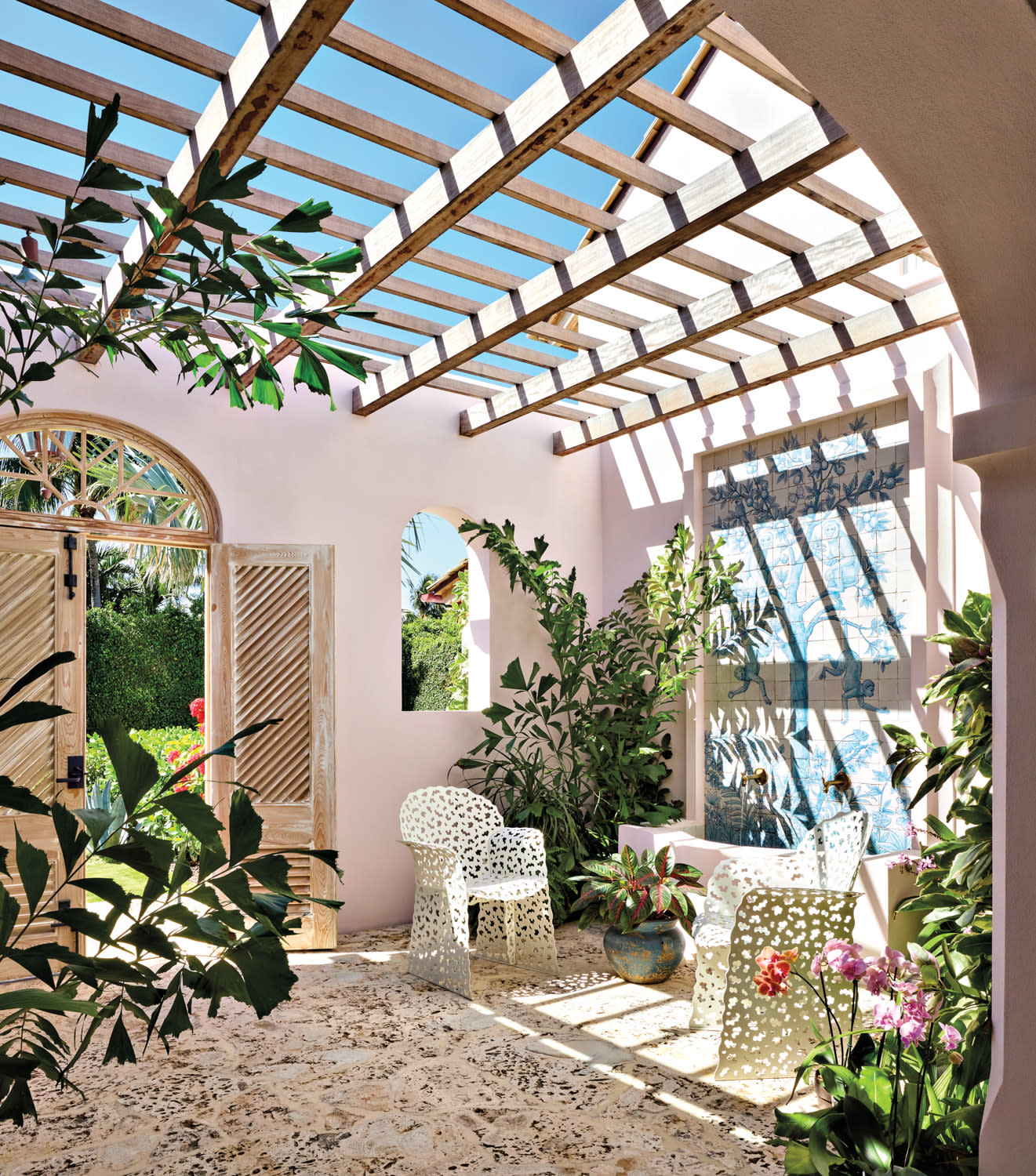 pink loggia with vintage chairs, a water fountain and a cypress awning