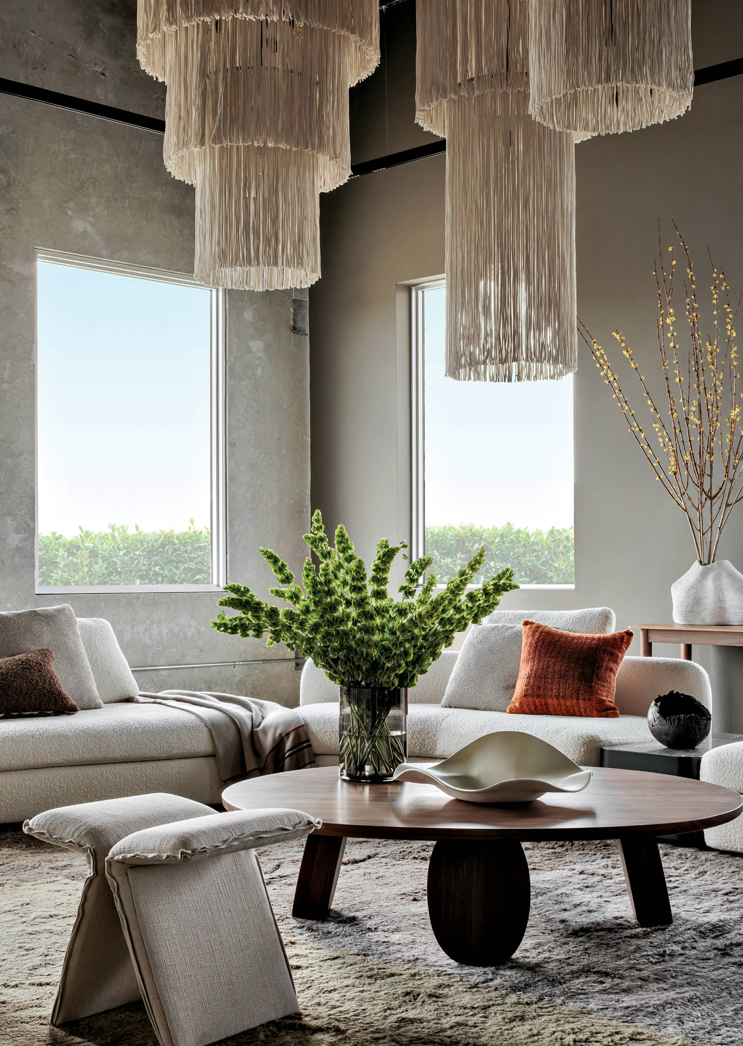 A sitting area decorated with couches, a coffee table and long draping chandeliers.