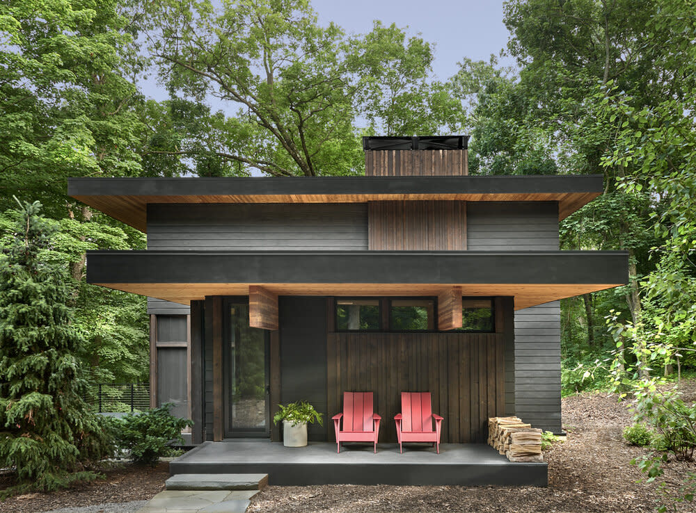 Front porch with two red chairs surrounded by nature