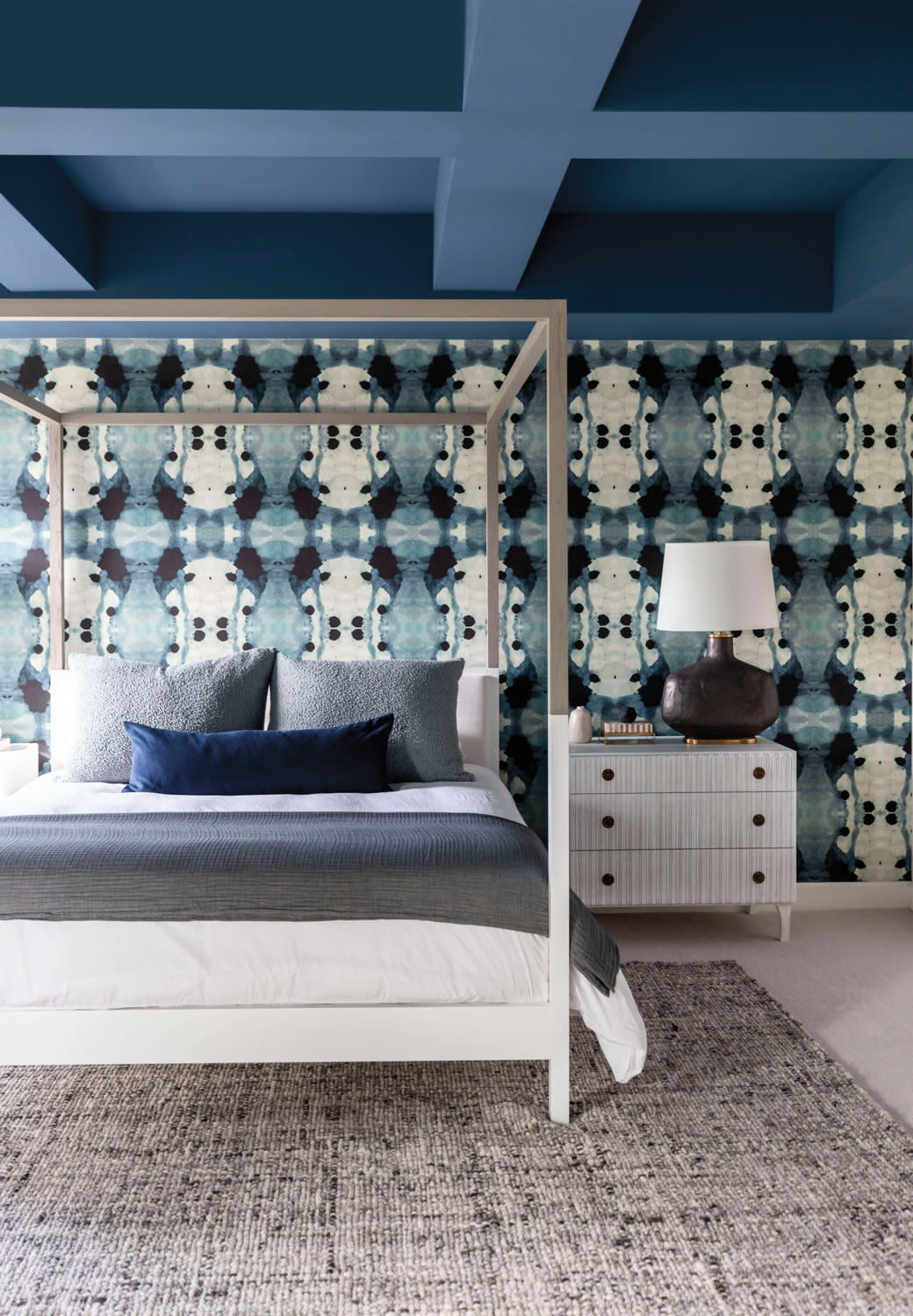 Bedroom with graphic blue-and-white wallpaper and coffered ceiling coated in blue paint.