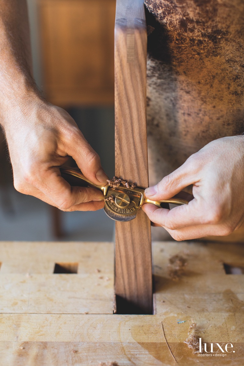 Using a plane, he shapes one of his pieces.