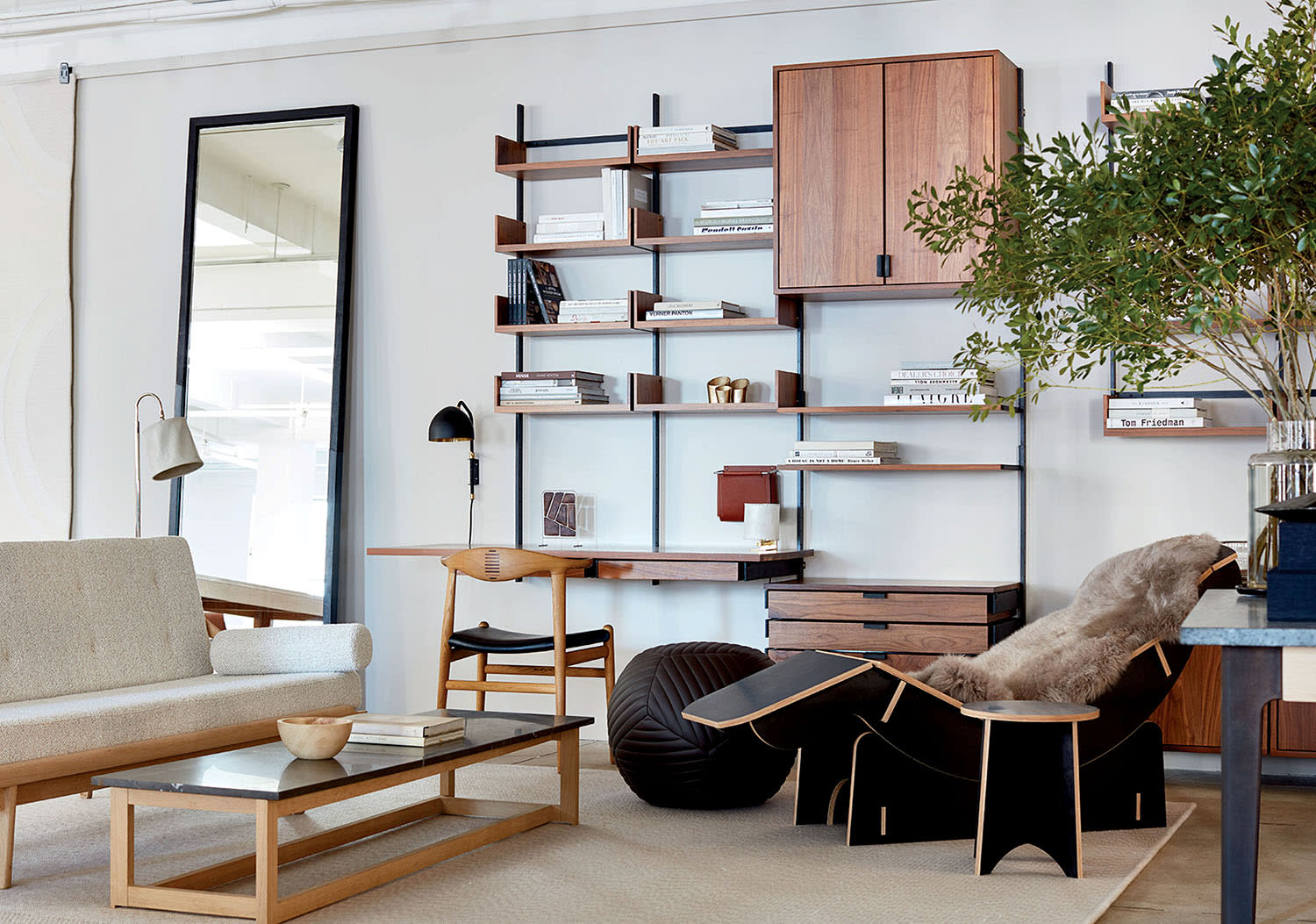 A living room with couch, coffee table, desk with book shelves and a reclining chair.