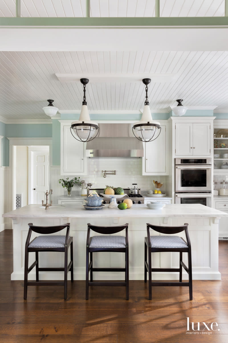 Pendant lights hang over a paneled kitchen island.